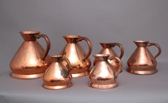 A set of six highly decorative 19th Century copper measuring jugs