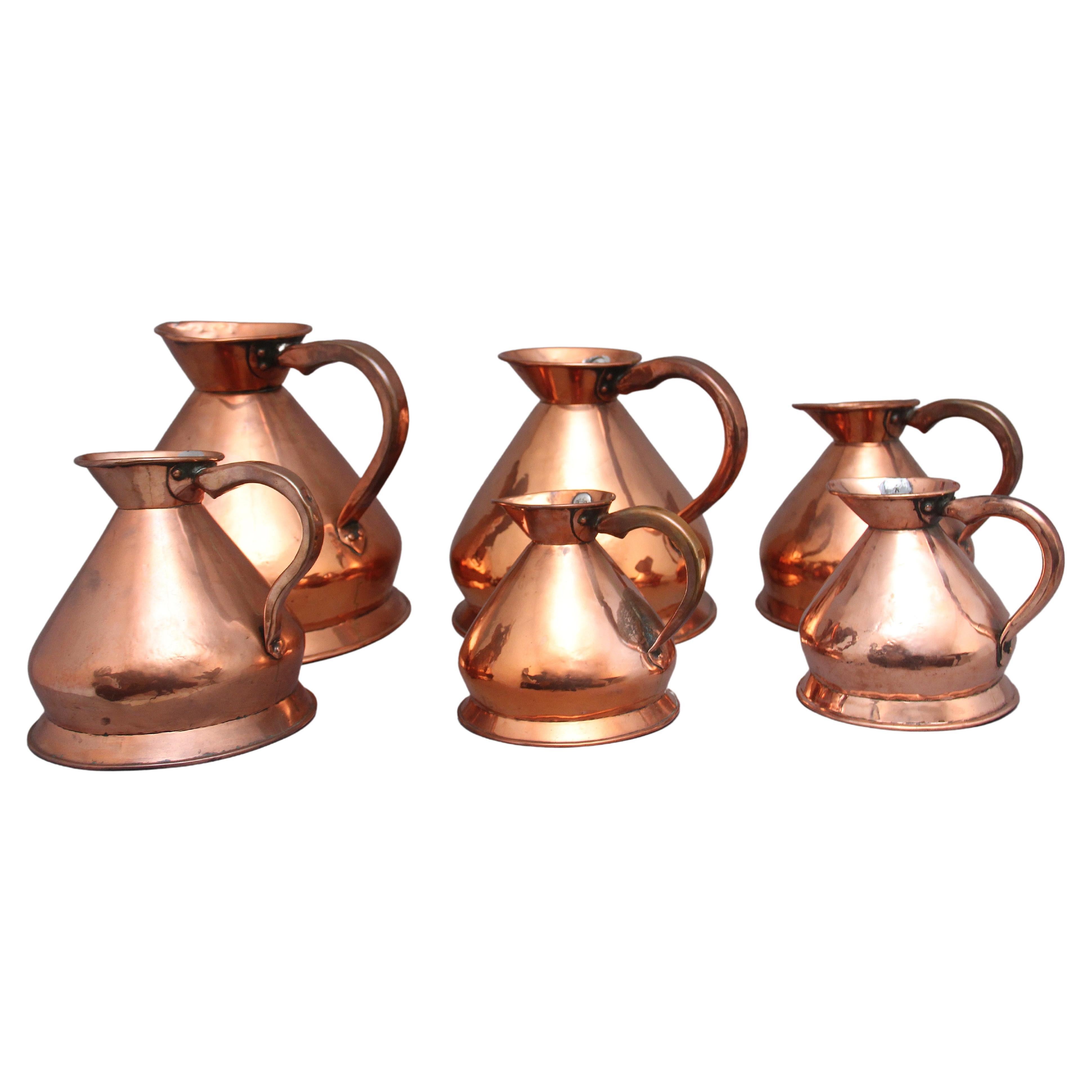 A set of six highly decorative 19th Century copper measuring jugs For Sale