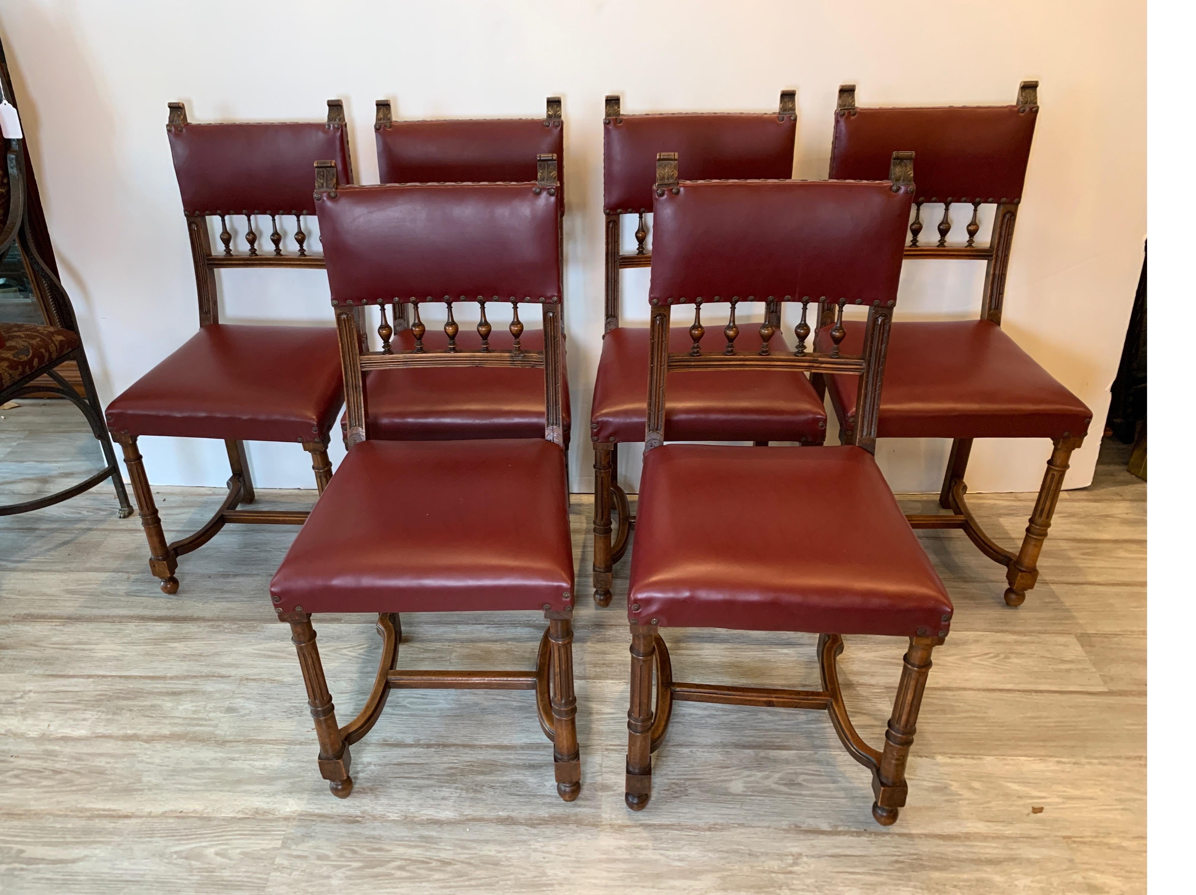 A set of six walnut dining chairs with padded seat and backs, the frames with a Jacobean style frames with hand carved details. One with an old repair, the frames are in a durable vinyl and can easily be recovered in the buyers new fabric, early