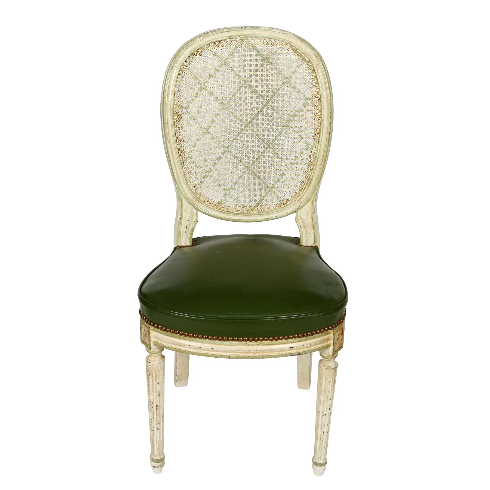 A set of six Louis XVI round, caned back dining chairs, with white painted frames, oval back with green diamond stencil pattern and green leather seats with nailhead trim.