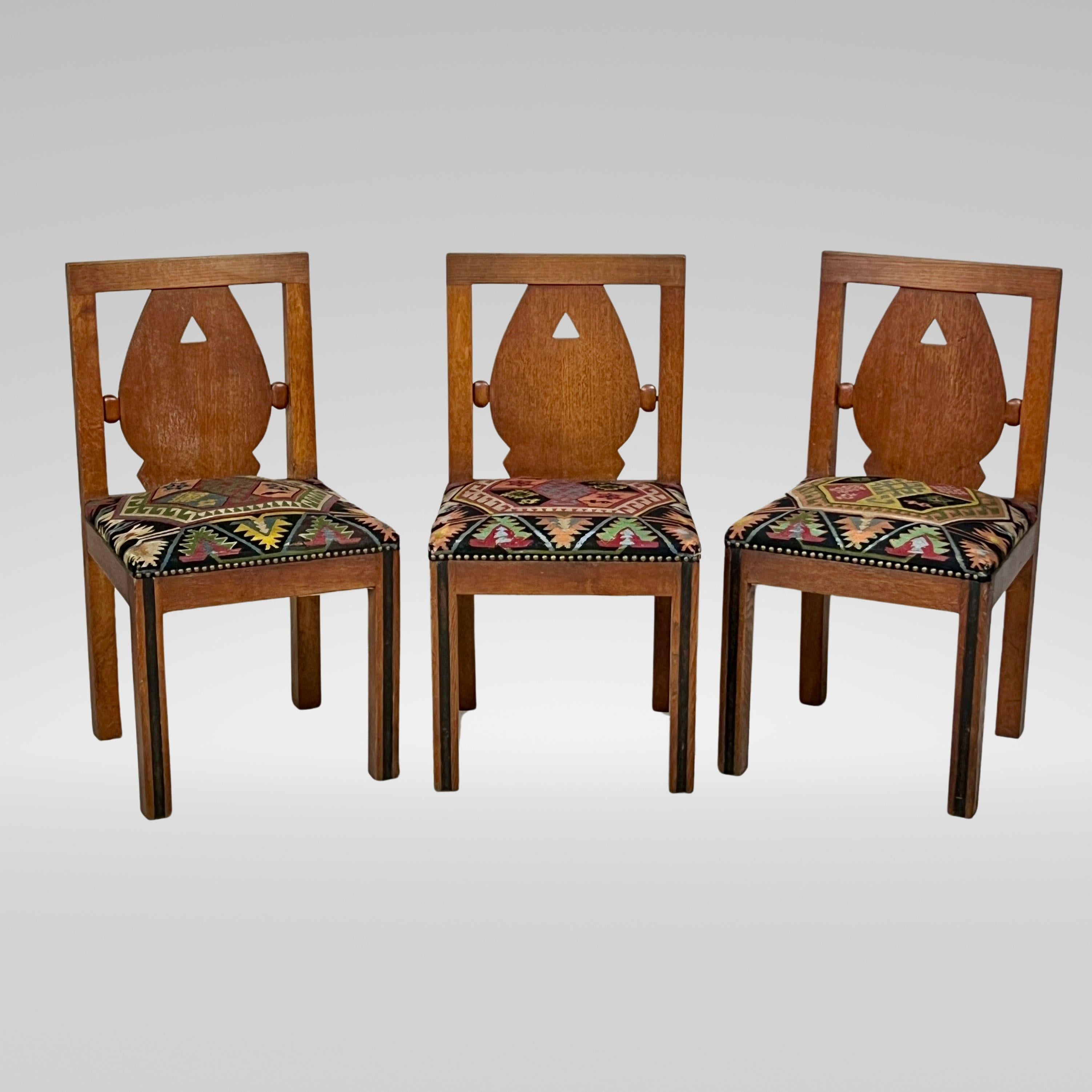 A Wonderful Set of Six Oak Art Deco and Kilim Dining Chairs. The rectangular back rest with inset shield and pierced triangular decoration is flanked with lozenge shaped detail. The kilim-covered seats are a standout feature, beautifully