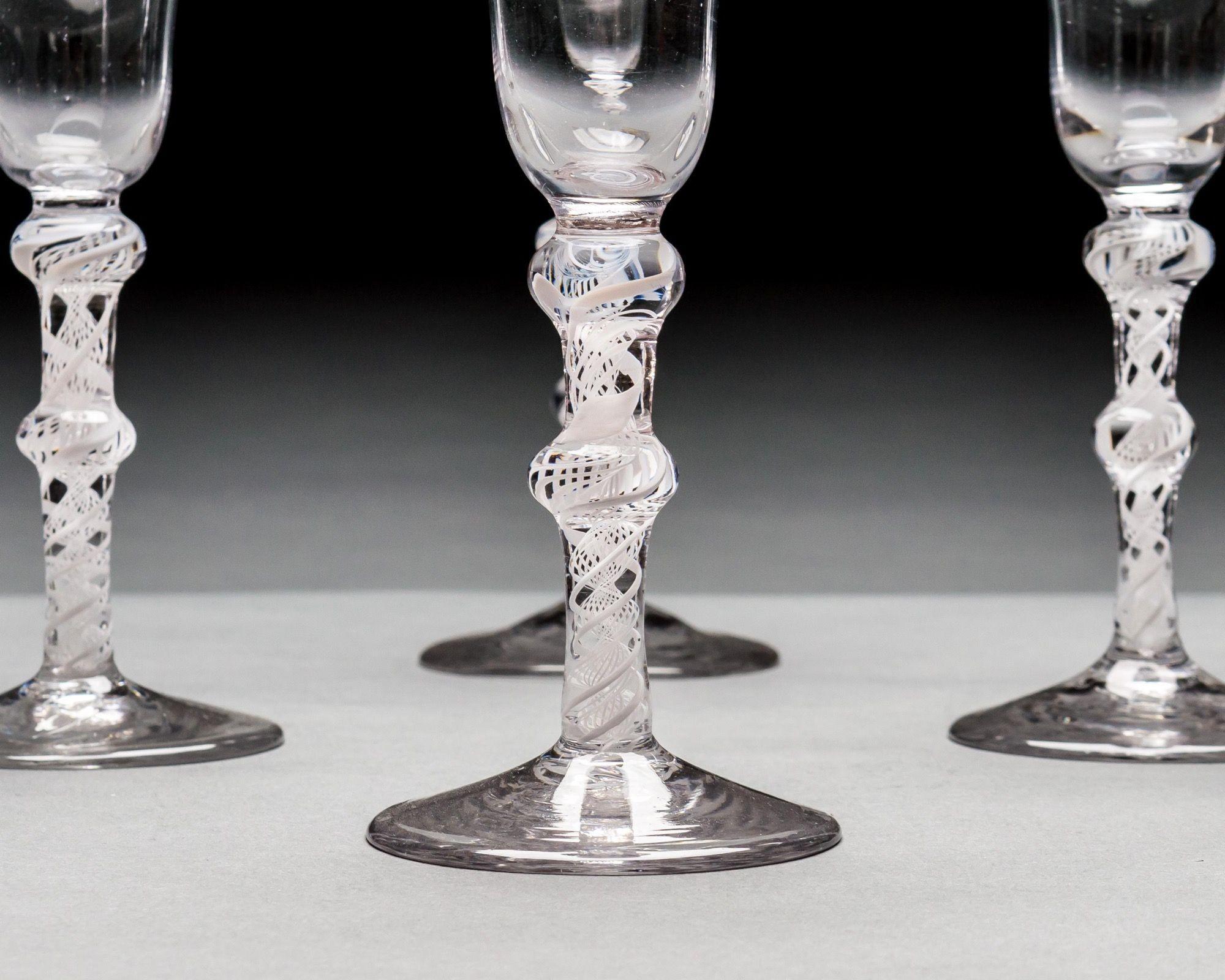 A set of six wine glasses with bell bowls supported by double knopped, double series opaque twist stems on plain conical feet.