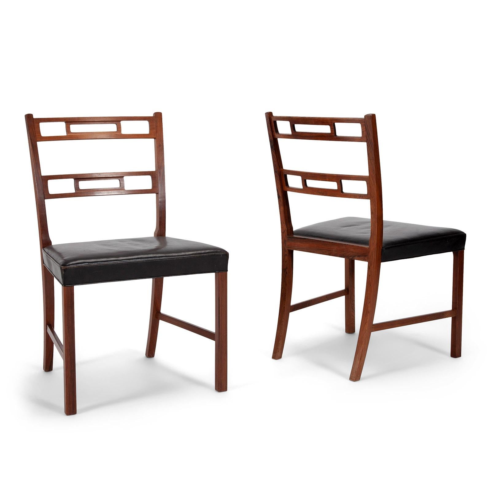 A set of refined dining chairs in Brazilian rosewood with seats upholstered in original black leather.
Designed by Ole Wanscher and expertly crafted by master cabinetmaker A. J. Iversen in Copenhagen, Denmark