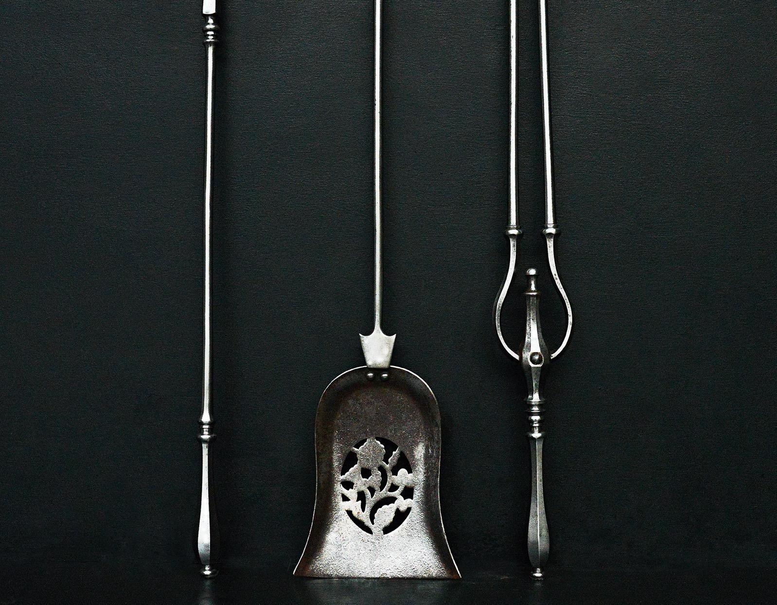 A delicate set of three steel fire irons, the shovel with pierced decoration, faceted handles above. English, early 19th century.

Length:	775 mm      	30 ½