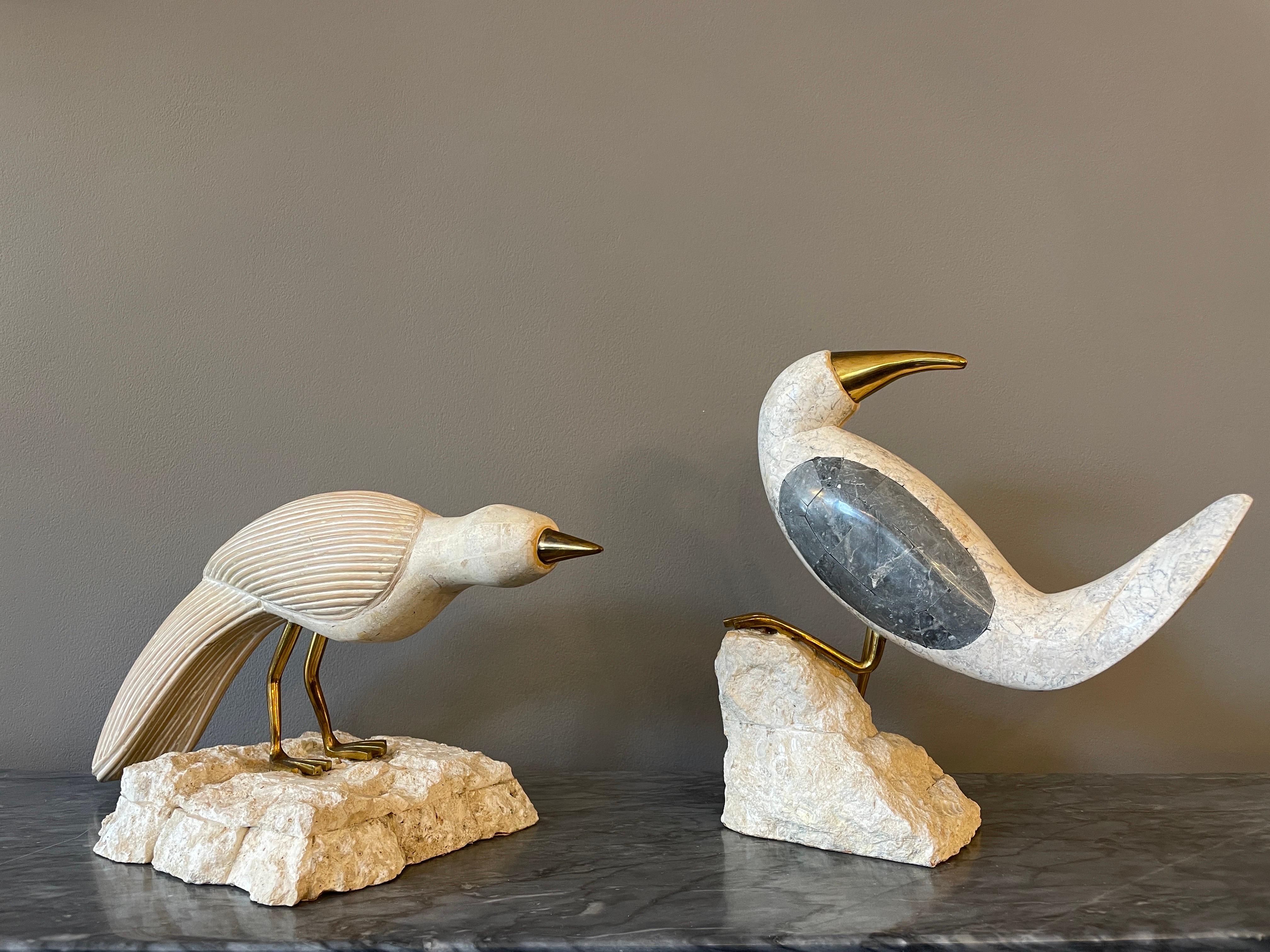 A set or matched pair of stone and tessellated marble birds with brass beaks and feet. Perched on stylised rocks. A tessellation or tiling is the covering of a surface, using one or more geometric shapes, called tiles, with no overlaps and no gaps.