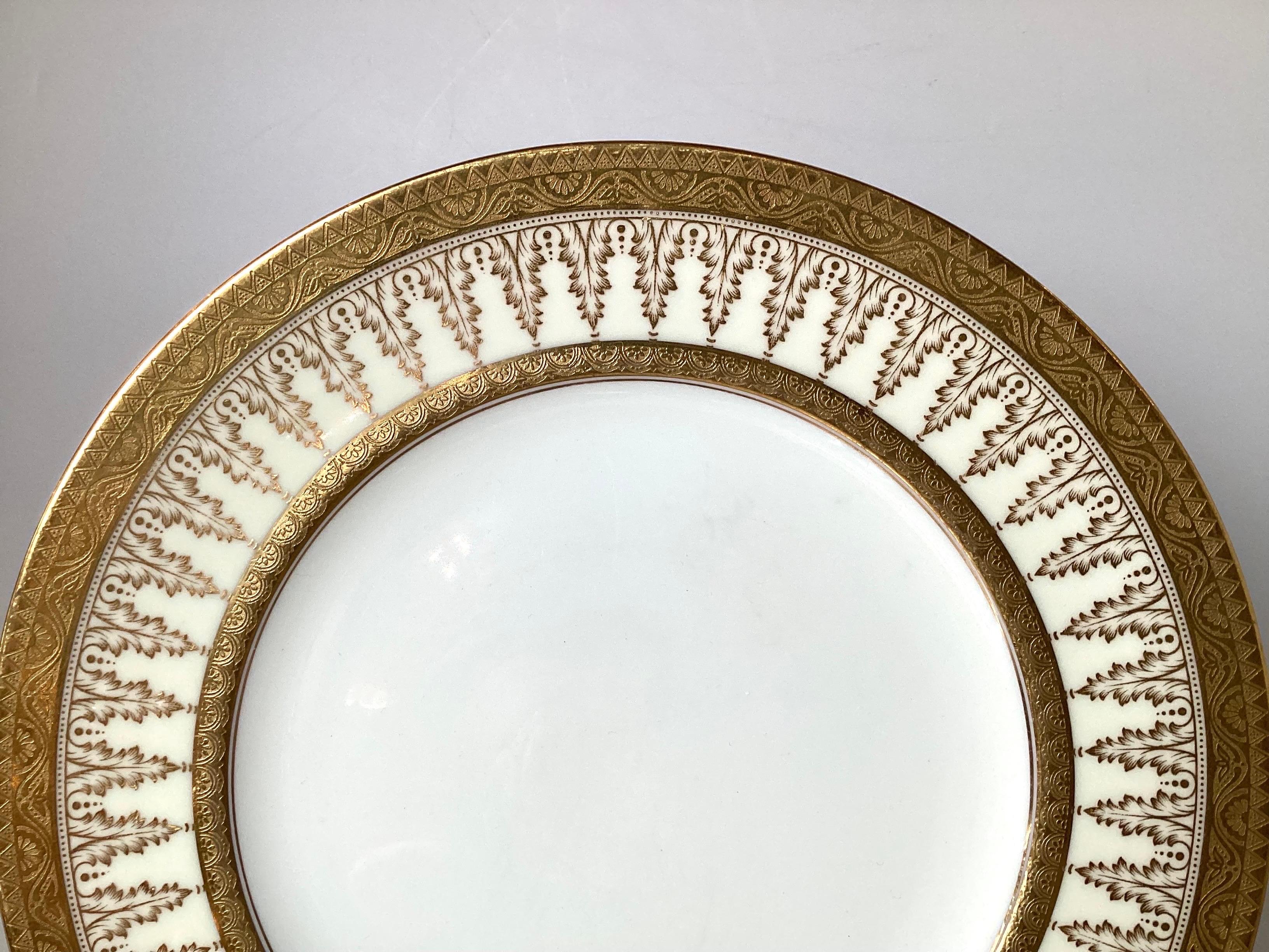 Un ensemble de dix élégantes assiettes de service de l'époque d'Eleg, fabriquées par Cauldon. Les bordures en or avec un décor de feuilles d'acanthe répétées, vendues par Tiffany, Angleterre, début du 20e siècle.