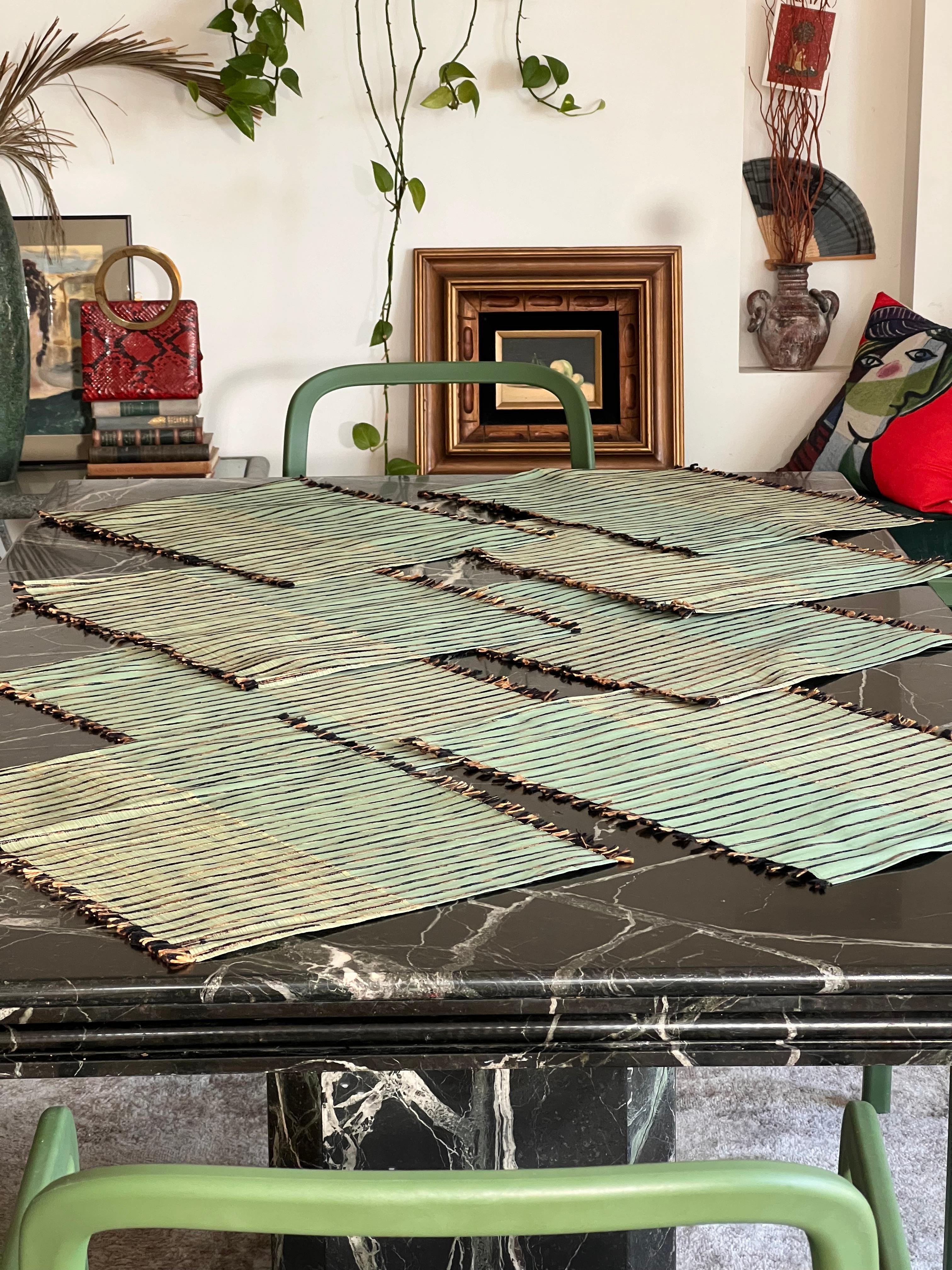 Ensemble de 9 sets de table et chemins de table en soie fine (100% soie thaïlandaise) par Vila CINI, Thaïlande, début des années quatre-vingt. Dans des tons de vert de mer, de mousse, d'étain et de caramel, avec un petit pompon sur le bord supérieur
