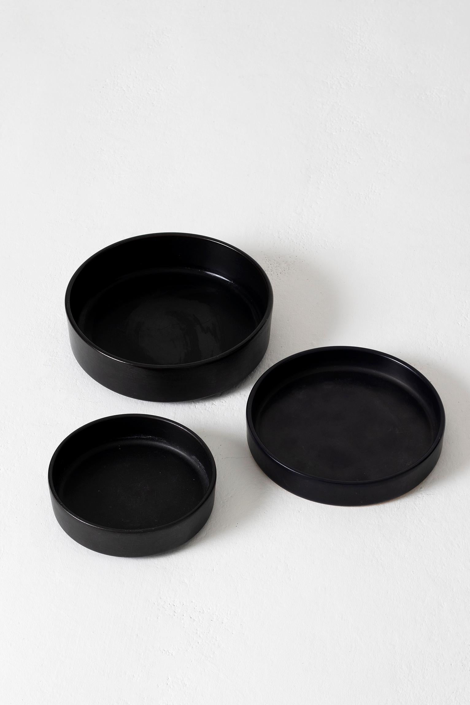 A set of three black ceramic bowls.
France, 1950s.