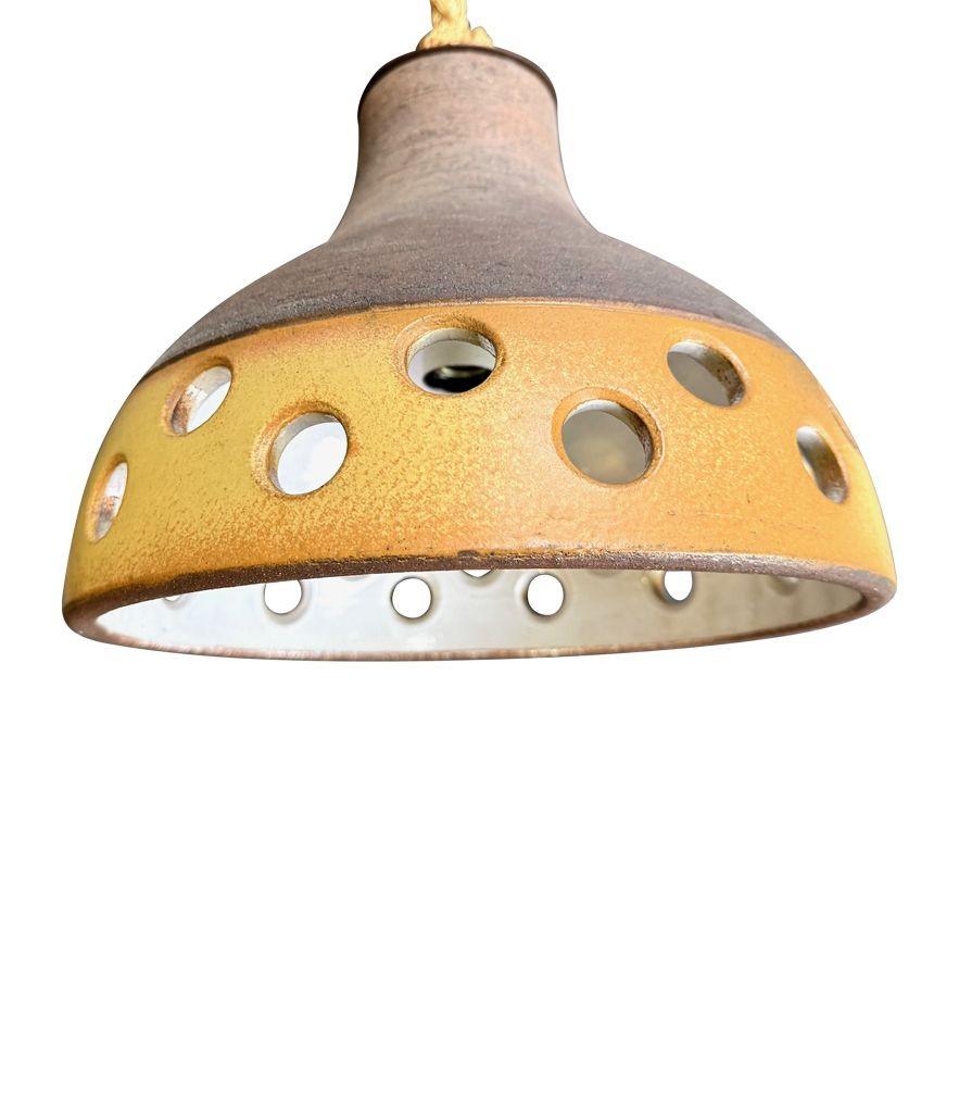 Ensemble de trois plafonniers en céramique émaillée française des années 1960, avec finition en émail biscuit sur le dessus, partie inférieure perforée en jaune et émail blanc à l'intérieur. Chacune est suspendue à une corde épaisse nouée avec une