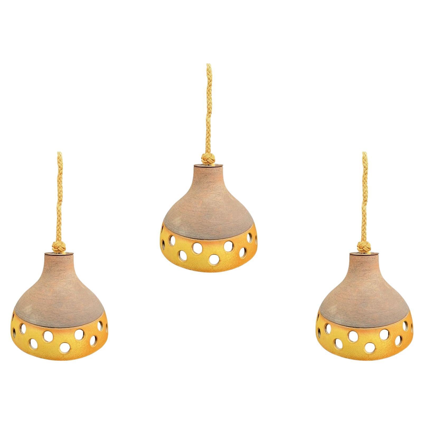 A set of three 1960s French glazed ceramic ceiling lights suspended from rope