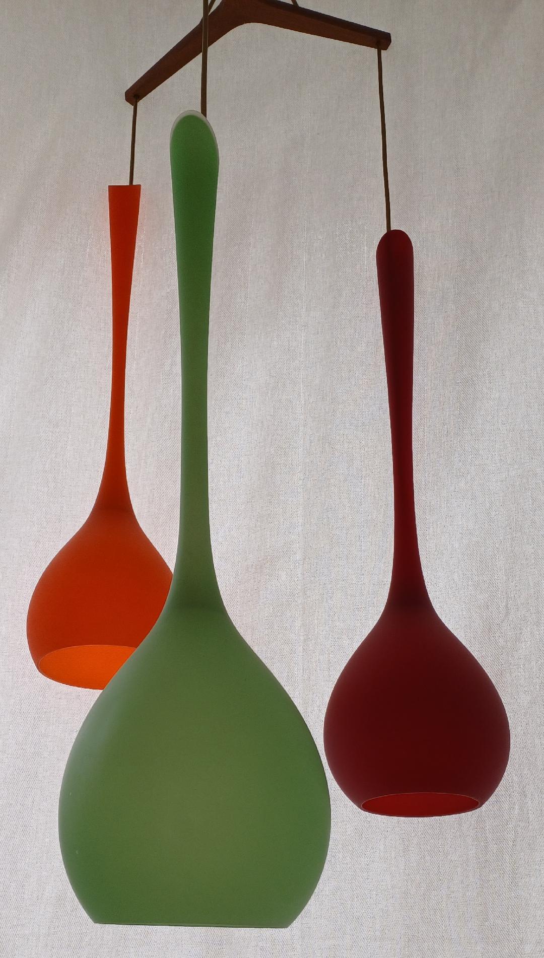 A set of three beautifully shaped Murano glass ceiling lights. Three different colours; green, orange and red, circa 1960s. The dimensions of the individual light is 74 cm in height and diameter is 19 cm. The support is in wood and the height of the