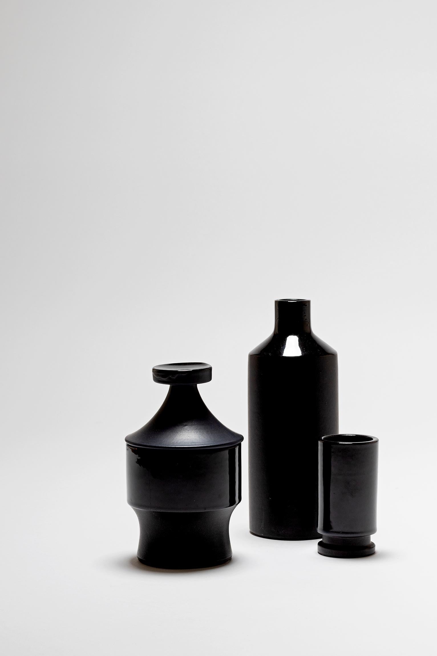 A set of three black ceramic vessels, by Lucerner Keramik
Switzerland, Lucerne, 1950s
Stamped with the maker's mark and inventory number
Bottle: 21 cm tall 
Lidded box: 17 cm tall 
Smaller vase: 10 cm tall.