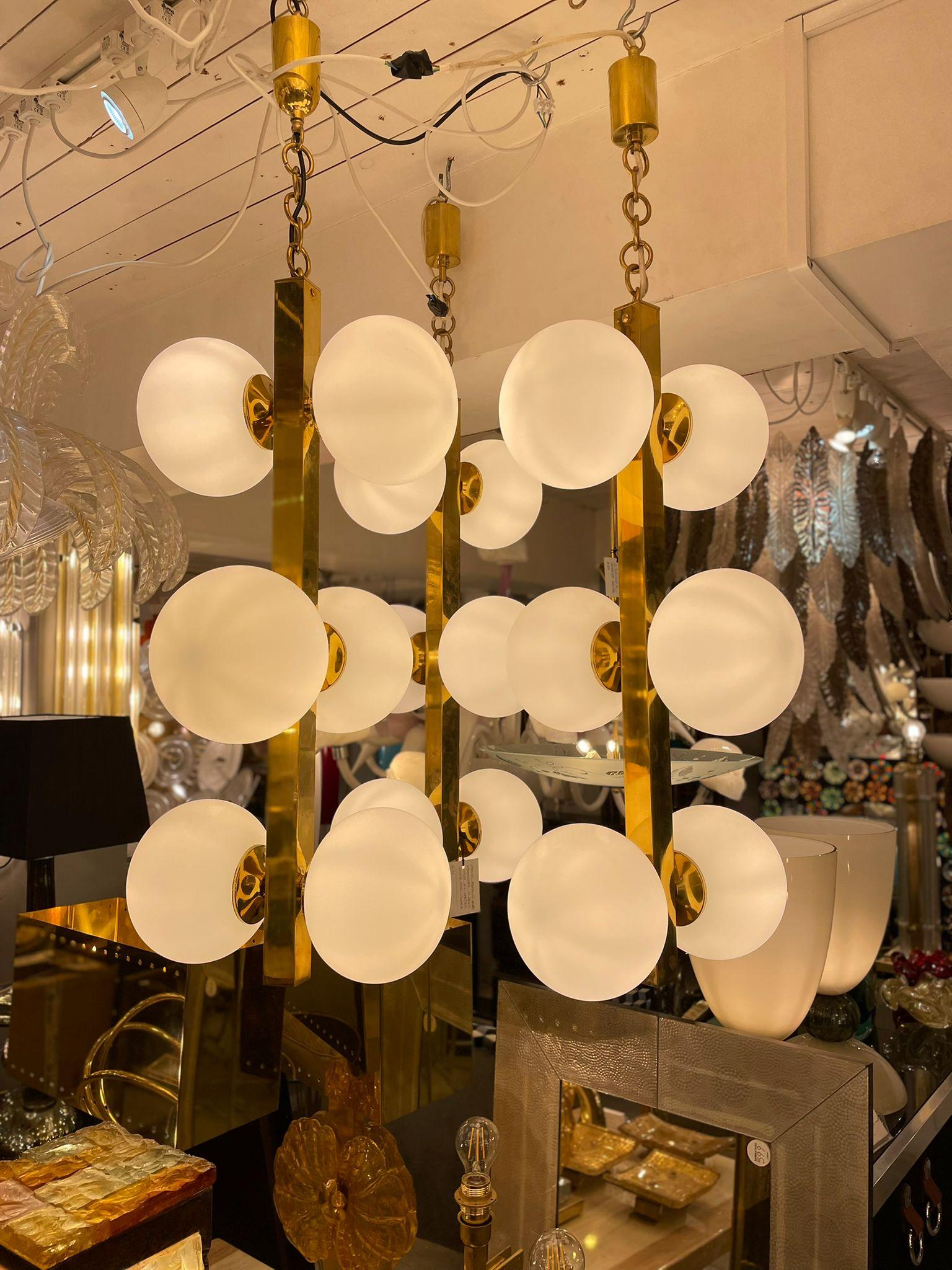 An elegant set of three chandelier in brass with white glass shades. Italy circa 1960s.

Items can be sold individually.