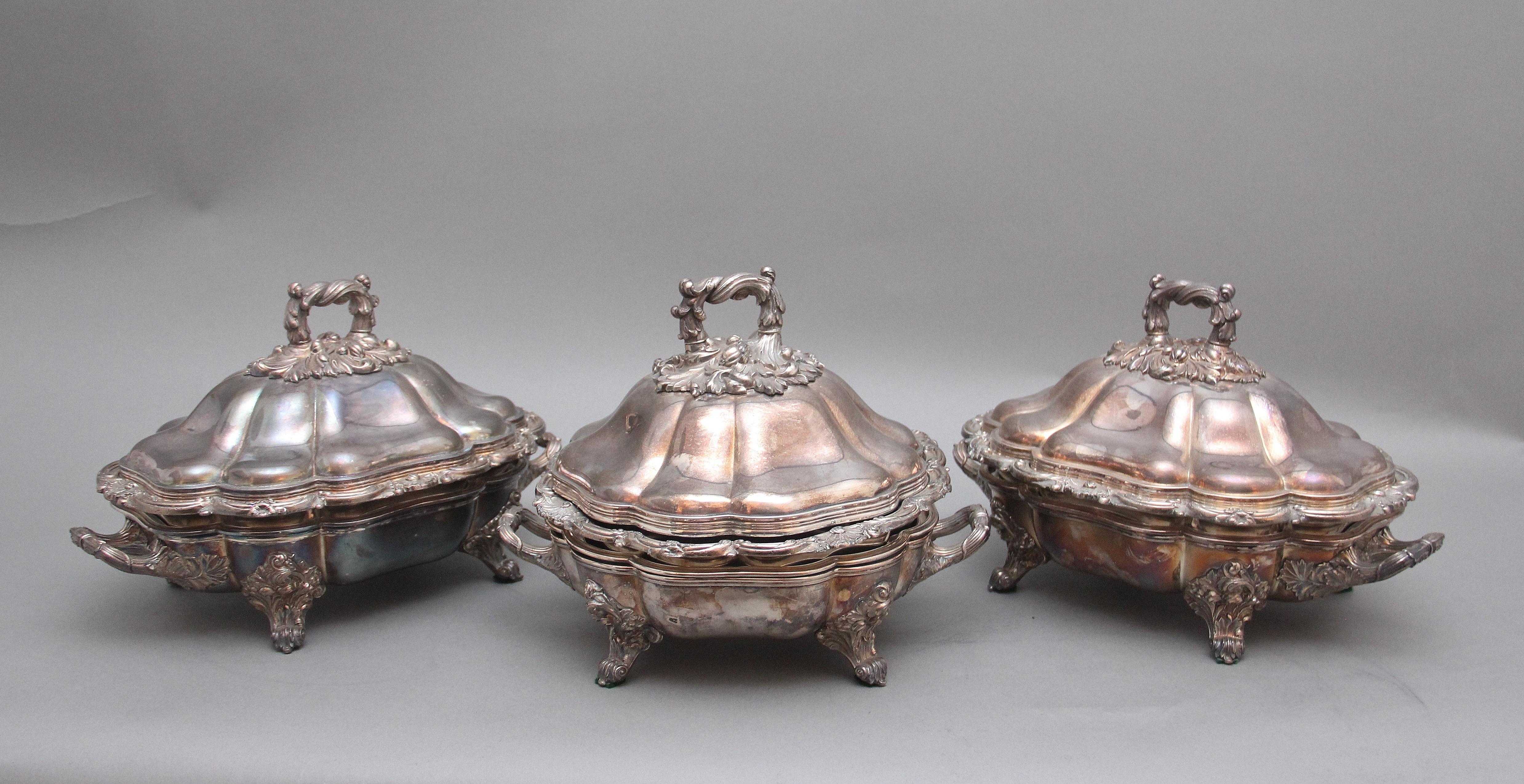 A set of three early 19th Century silver plated Old Sheffield tureens, all three having domed covered lids with highly decorative acanthus leaf handle, the same style handle is at each side of the dishes, supported on four intricate engraved feet,