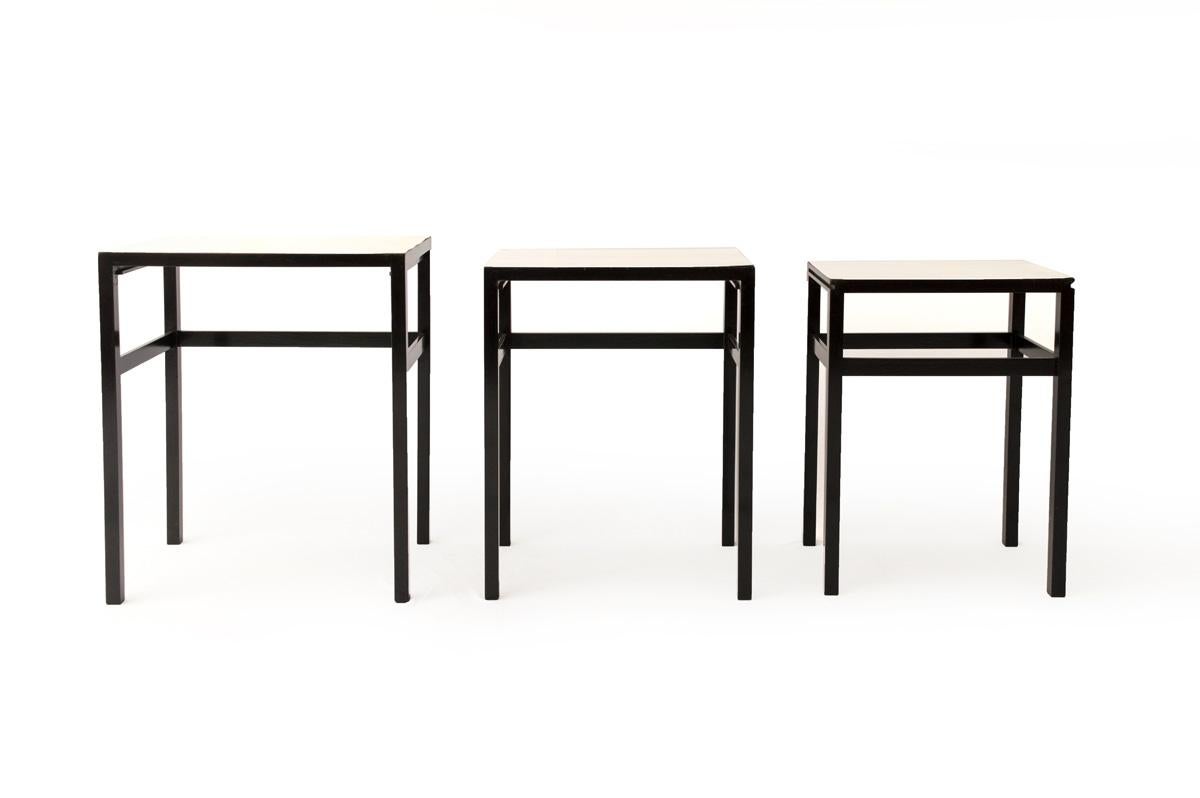 The set consisting of three black lacquered solid hardwood nesting tables with white Formica tops.