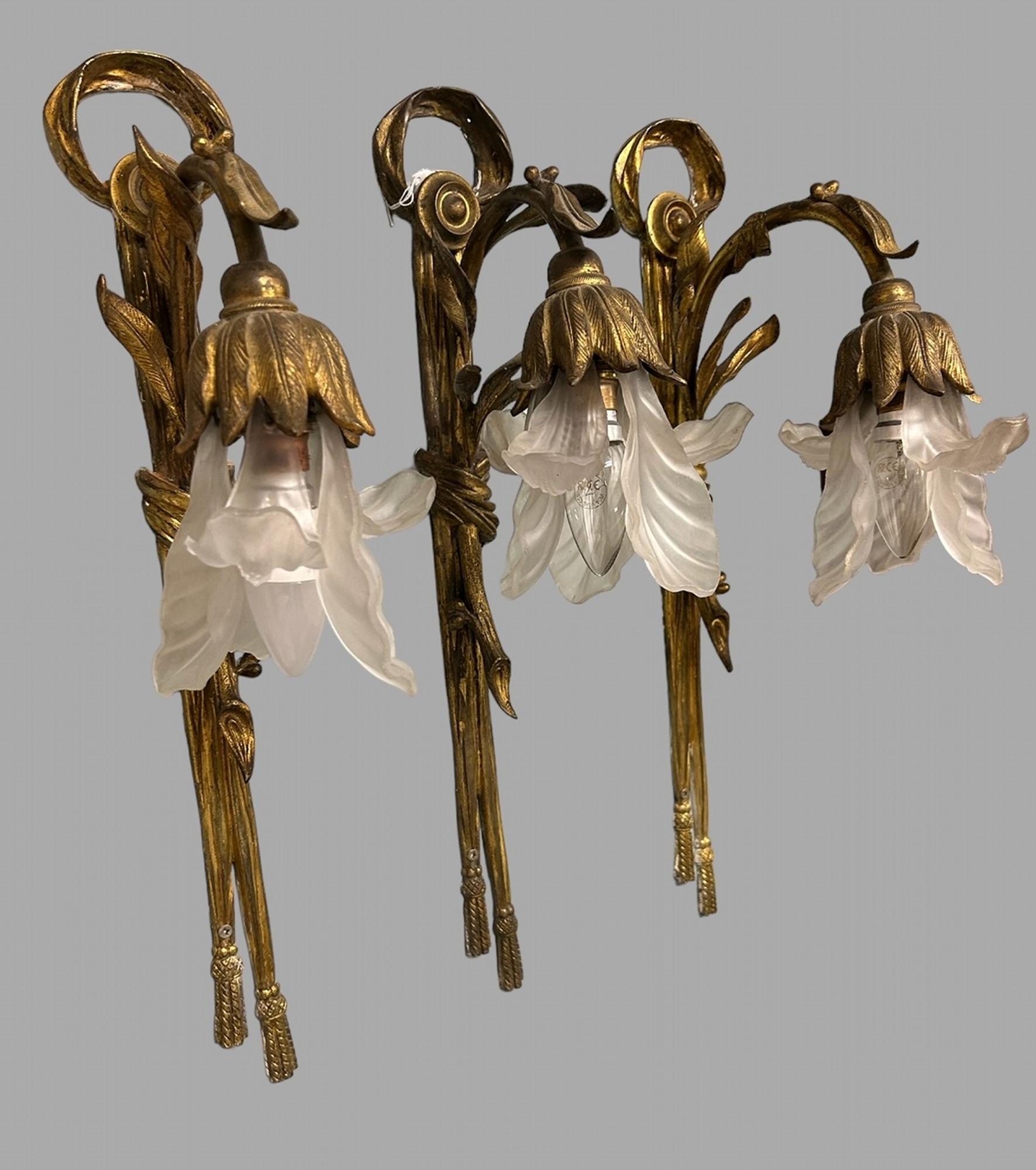 Ein attraktives Set aus drei Wandleuchten in Form einer offenen Lilie. Die vergoldeten und gläsernen Beleuchtungskörper sind an einem vergoldeten Seil mit Quasten befestigt. Erneut verkabelt und geprüft