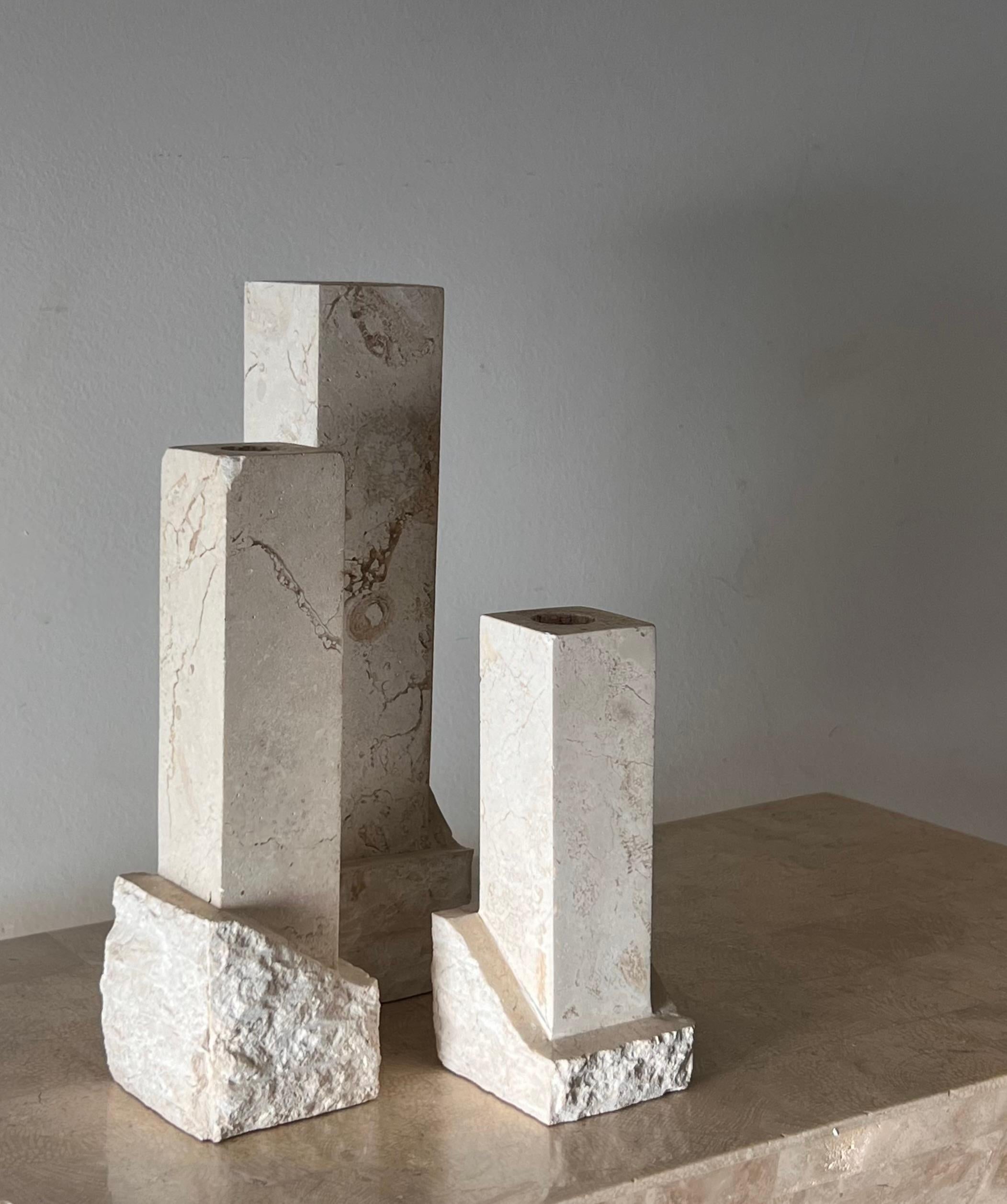 A set of three fossil and tessellated stone “ruins” candlesticks by Renoir Designs, late 20th century. This postmodern trio emulates the neoclassical sensibilities of Ancient Greece and Rome while firmly boasting a postmodern aesthetic in embracing