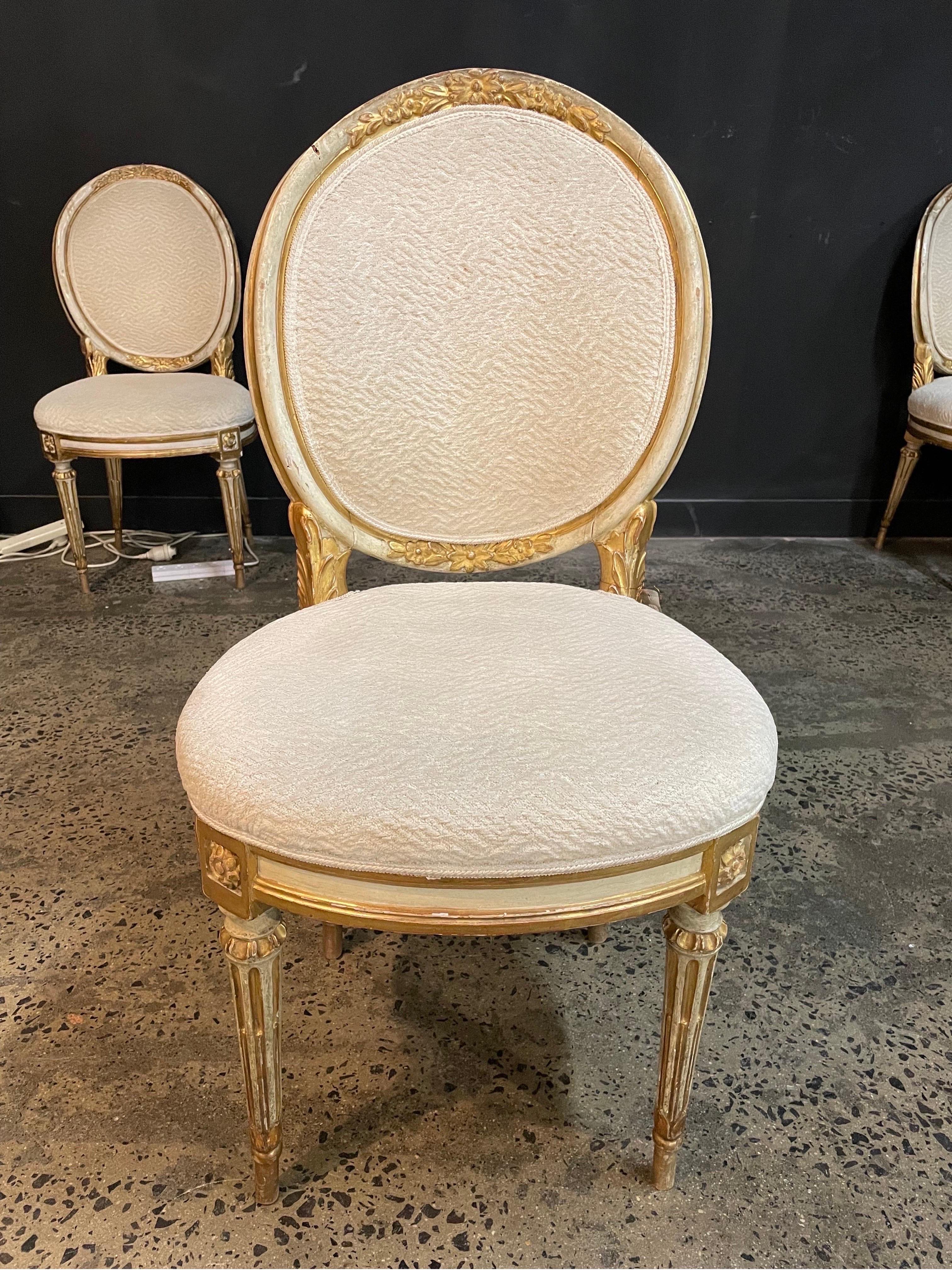A set of twelve Italian painted and parcel gilt Louis XVI Style dining chairs, 19th century

Tablet back chairs with floral carved details raised on fluted legs with rosette embellishments, upholstered in textured cream chenille fabric.

Provenance: