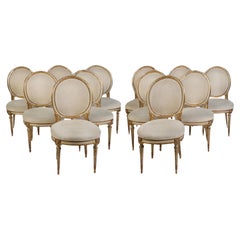 Ensemble de douze chaises de salle à manger italiennes peintes et dorées à la feuille de style Louis XVI