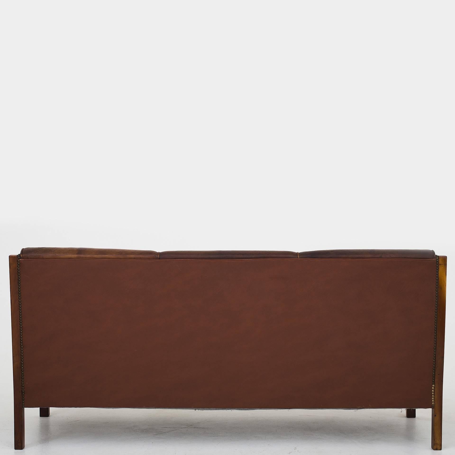 Two chairs and matching three-seat sofa in original, natural Niger leather with nails in brass. Frame in Cuba mahogany. Unknown Danish cabinetmaker, circa 1930.