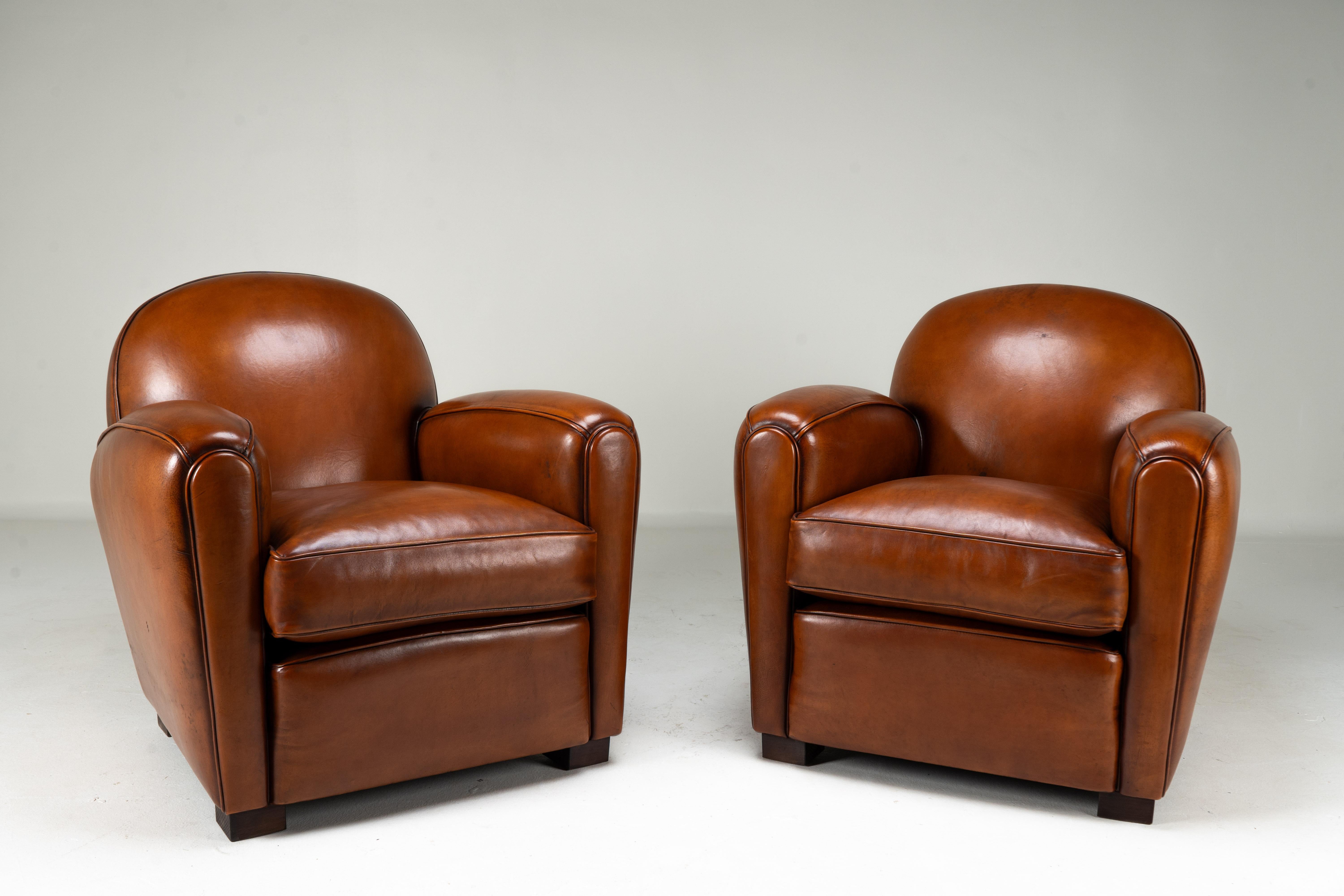 This set of two pairs of contemporary French Art Deco club chairs is a special find. With a design dating to the Deco/ Moderne movement of the 1920s-1940s, these chairs define an era of Parisian style. The tasteful nut-brown color has a beautiful