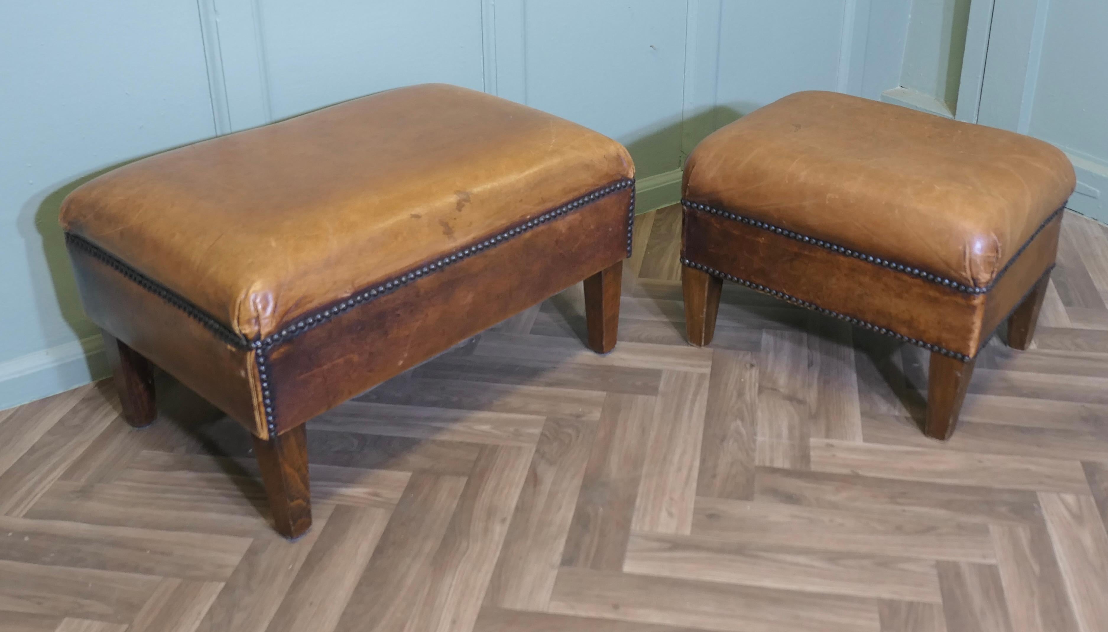 Ein Satz von zwei stabilen Fußhockern aus Leder für die Bibliothek 

Dieses sehr attraktive Vintage-Duo ist mit sehr weichem, braunem Nietenleder gepolstert und hat kurze Beine

Ein schönes Paar, die Hocker sind in einem sehr guten gealterten und