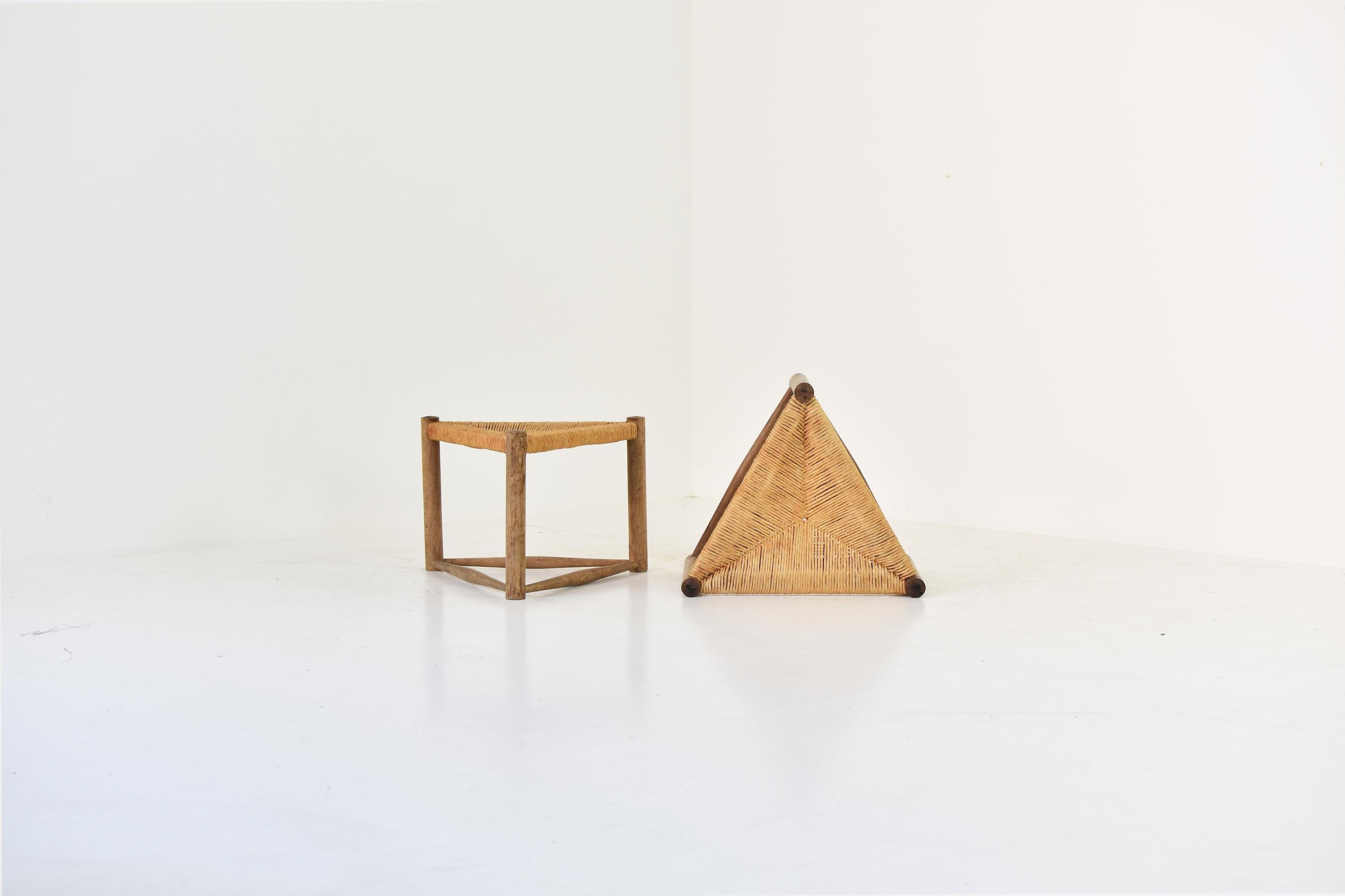 A set of two triangle shaped stools from France, 1950s. These stools features paper cord seats and stained solid wood base structures. Very good and original condition with only minor wear. Attributed to Charlotte Perriand.