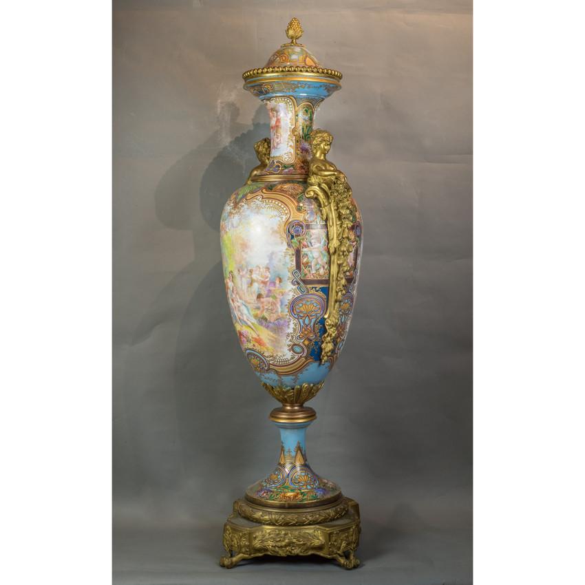 Espectacular urna de Sèvres, muy ornamentada, de estilo artesanal. Escenas de jardín de doncellas y putti hábilmente pintadas a mano a ambos lados. Sobre un fondo turquesa hay flores de vivos colores, follaje, volutas y algunos pequeños retratos que