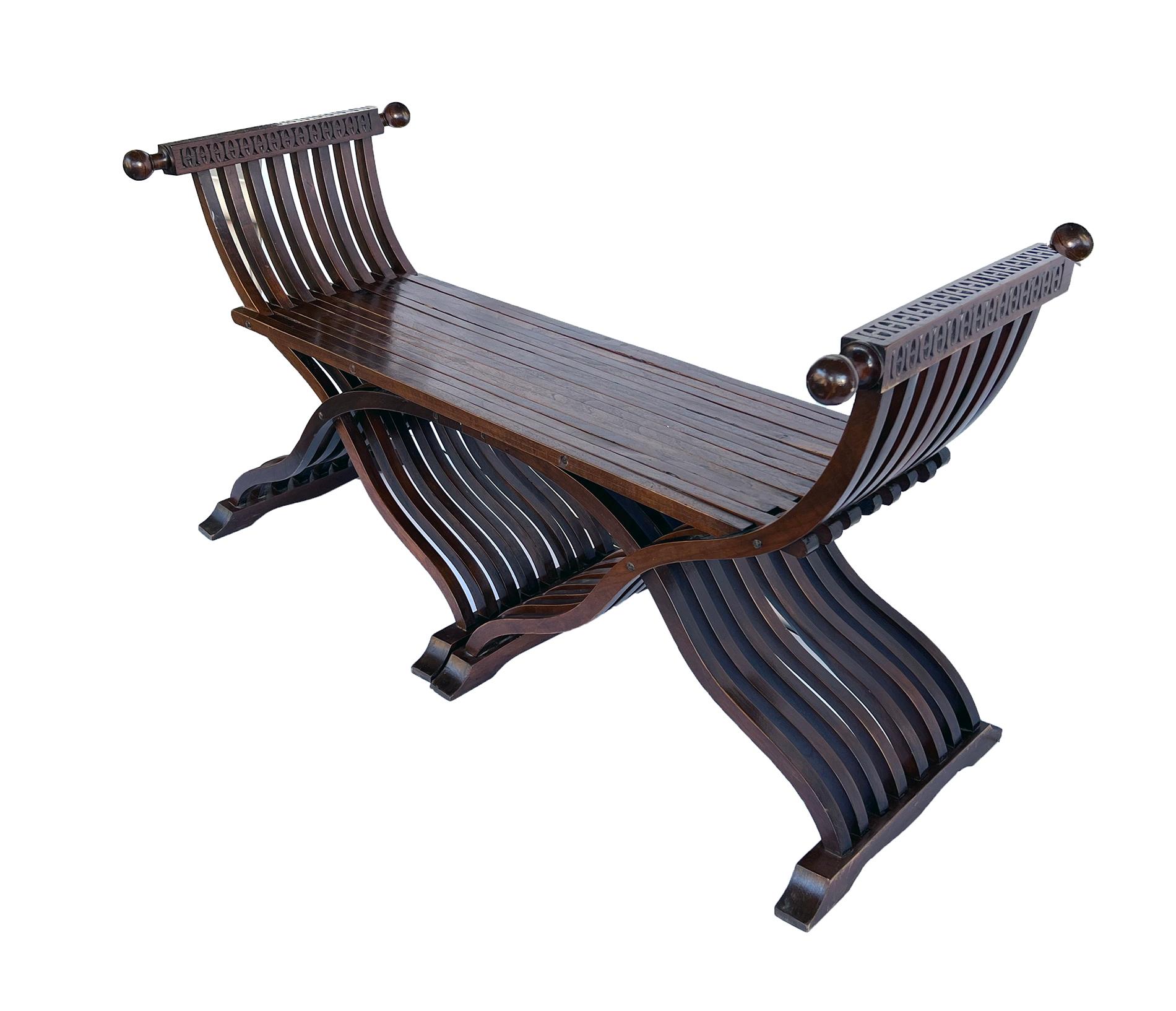 the long seat of slatted wood flanked by incurved arms with ball-form handholds; raised on a folding scissors double base; the term Savonarola derives from the chair on which the Savonarola used to sit in the convent of San Marco in Florence. The