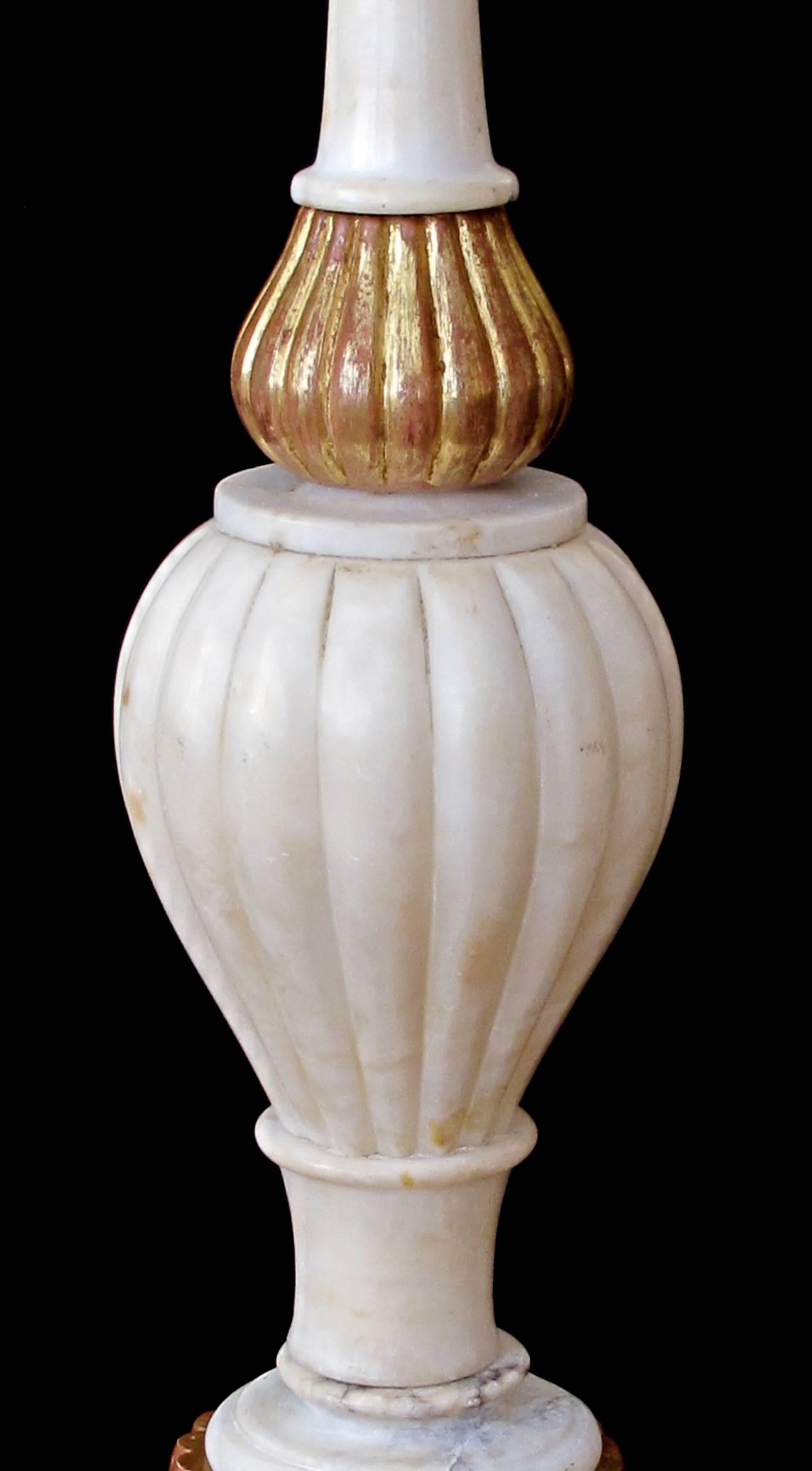 Each tall lamp with long neck above a ribbed bulbous body resting on a flared giltwood base.