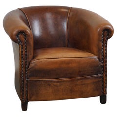 A sheep leather club armchair in good condition, modest in size.
