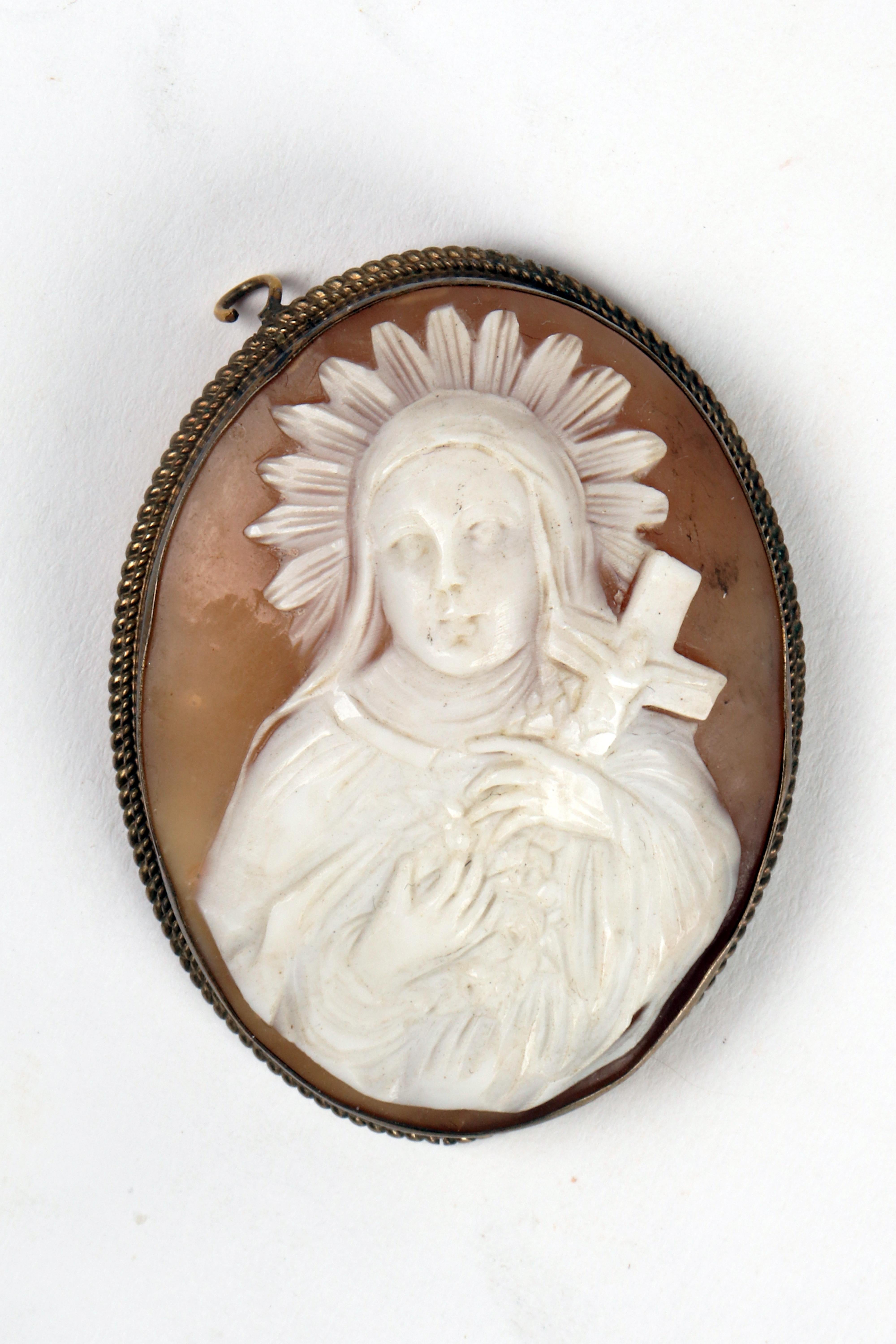 Oval shell cameo, mounted in golden metal depicting a figure of Santa holding a cross. The back has traces of attachments to a double chain, for use as a choker. England, late 19th century.