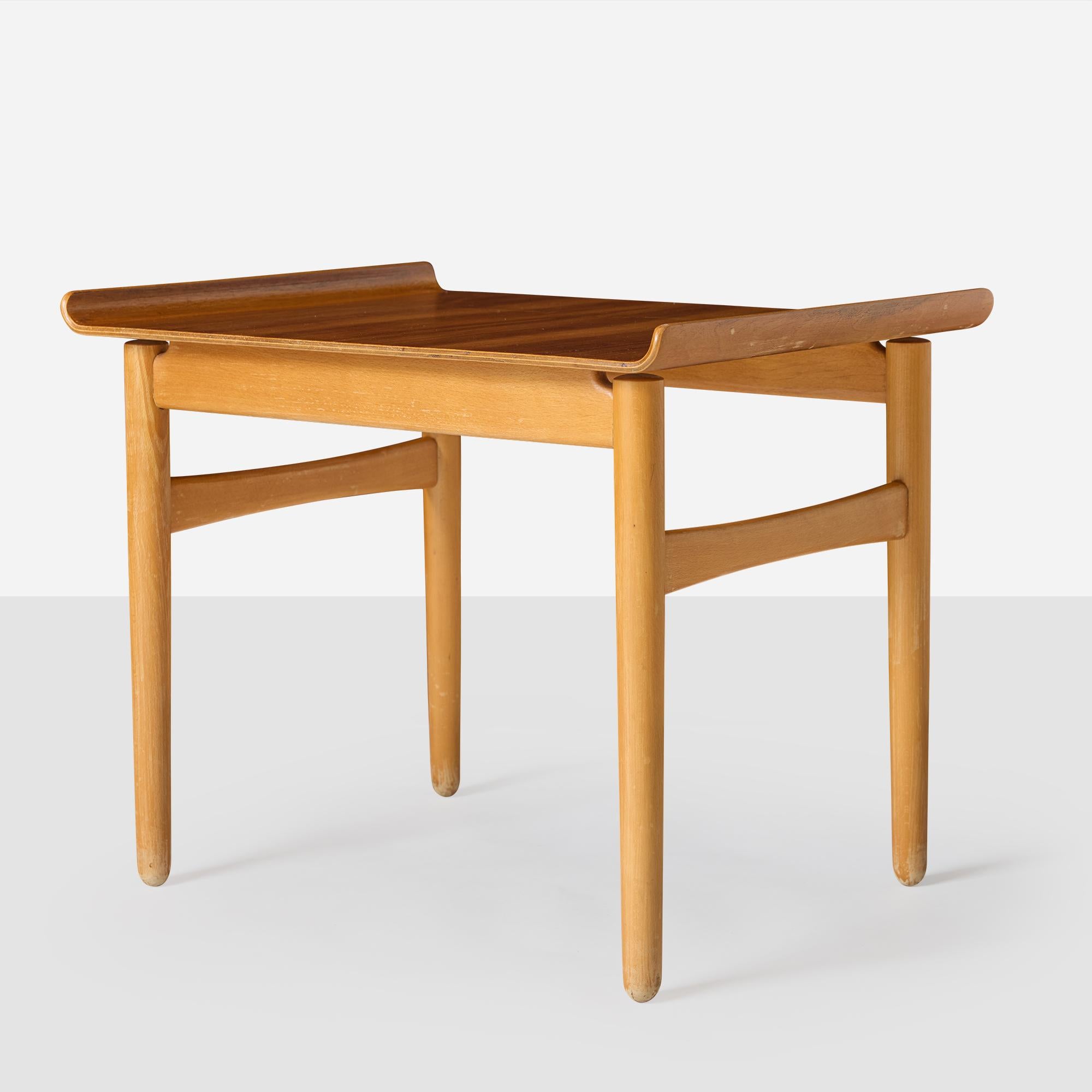 A 'Shell' series side table by Hans J. Wegner for Fritz Hansen, featuring a laminated walnut surface mounted on tapering beech legs. Made in Denmark, the table is in original condition with consistent wear from age and use, and the frame is solid