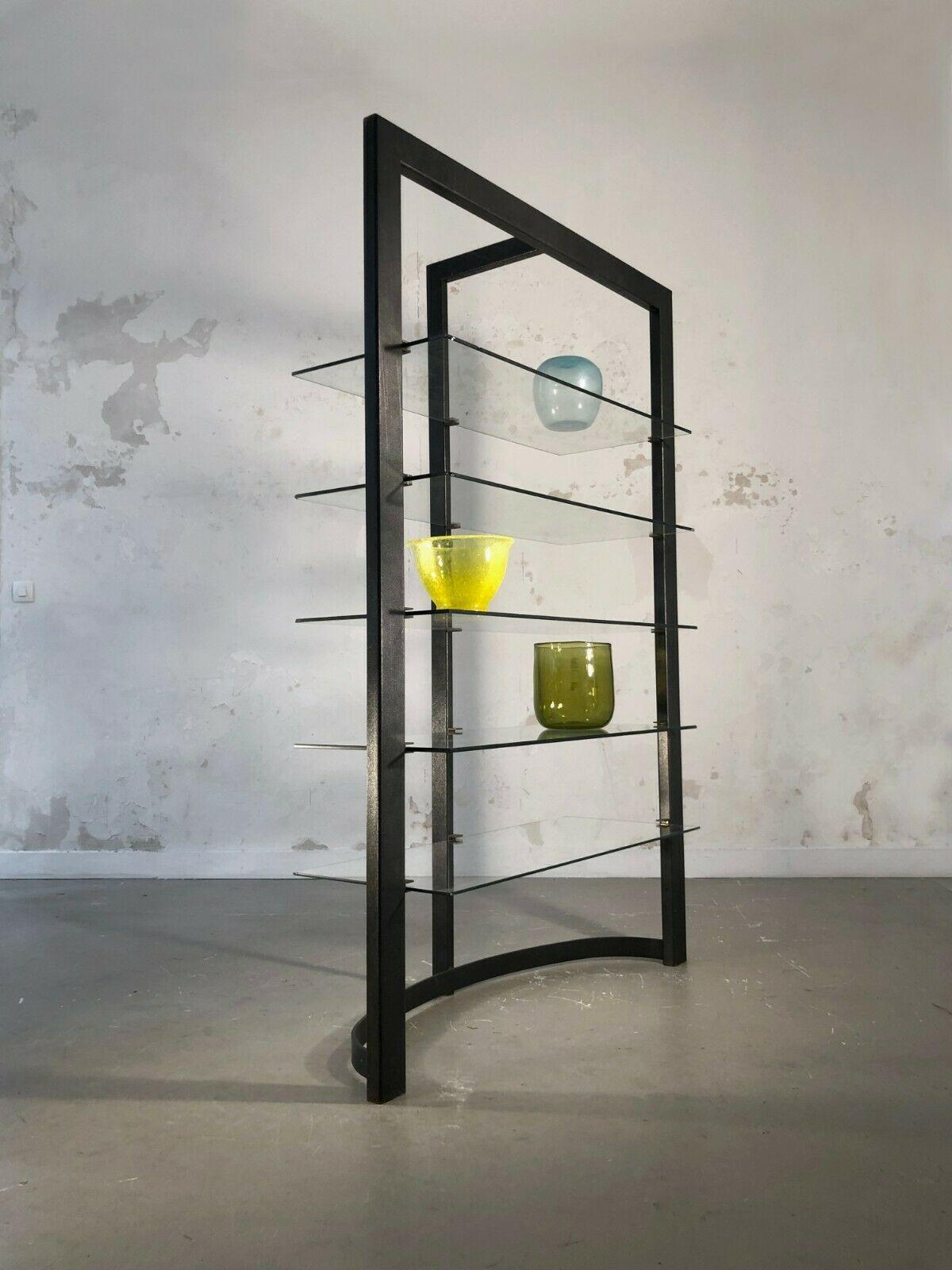 A radical shelving system or bookcase, Post-Modern, Constructivist, Memphis, Bauhaus, geometric asymmetric structure in steel lacquered in anthracite, with 5 shelves in glass suspended with brass or bronze square pieces, to be attributed, France,