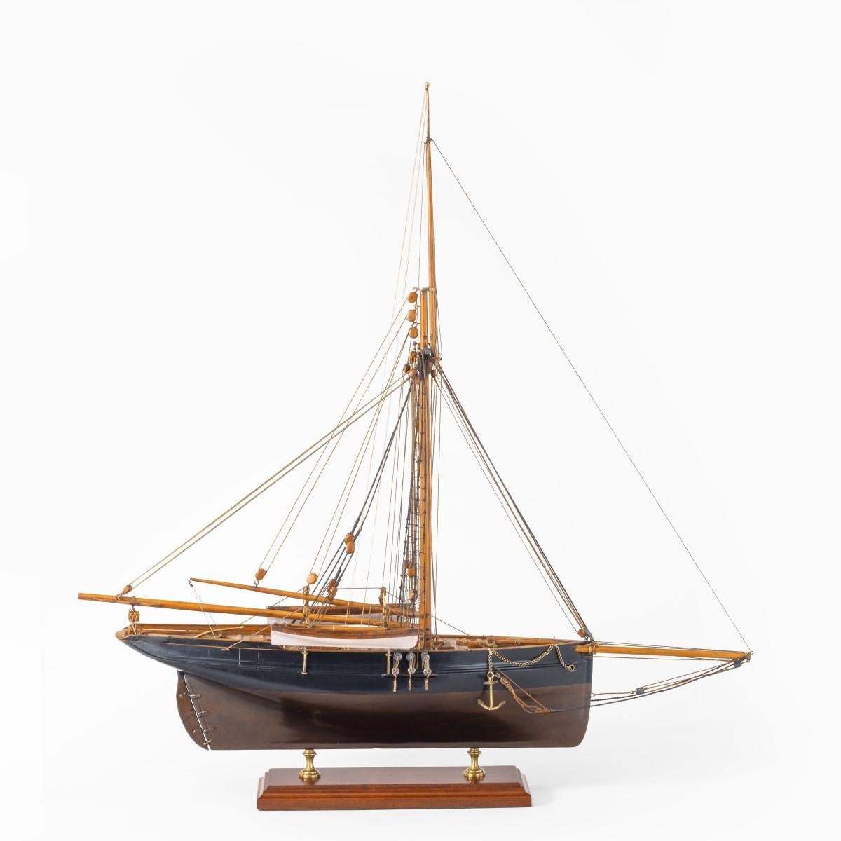 A shipyard model of a gaff-rigged Newhaven Smack, the hull carved from the solid with a scored deck, wood and metal fittings including metal anchors with chains, a hawse pipe and winch, deck lights, companionways, tiller, two boats sprung out on