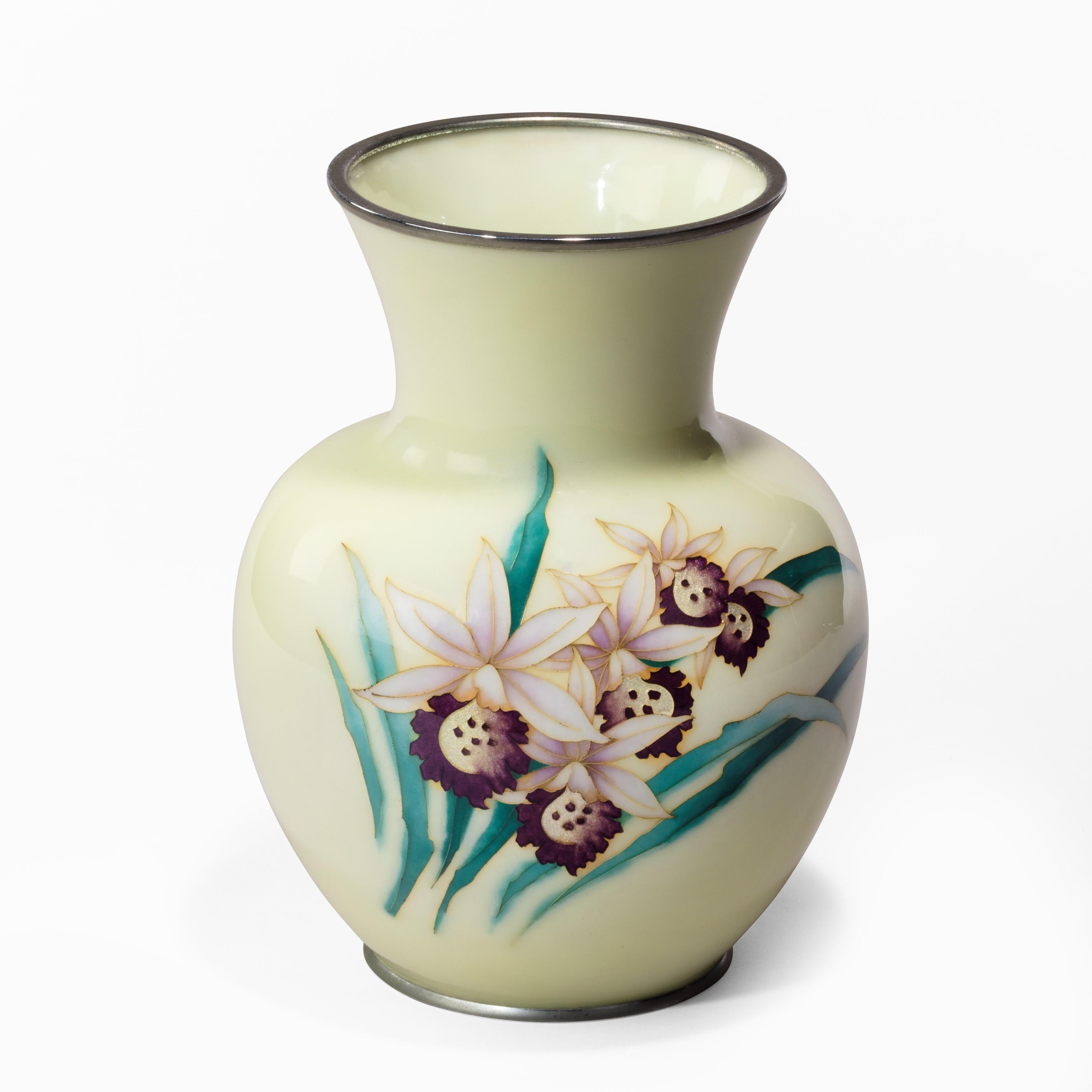 A Showa period pale yellow cloisonné vase by Tamura, decorated with a single spray of five purple and white orchids with silver foil gin-bari centres and inlaid silver wires, the mount stamped ‘Tamura’, Japanese, late 20th century.
  