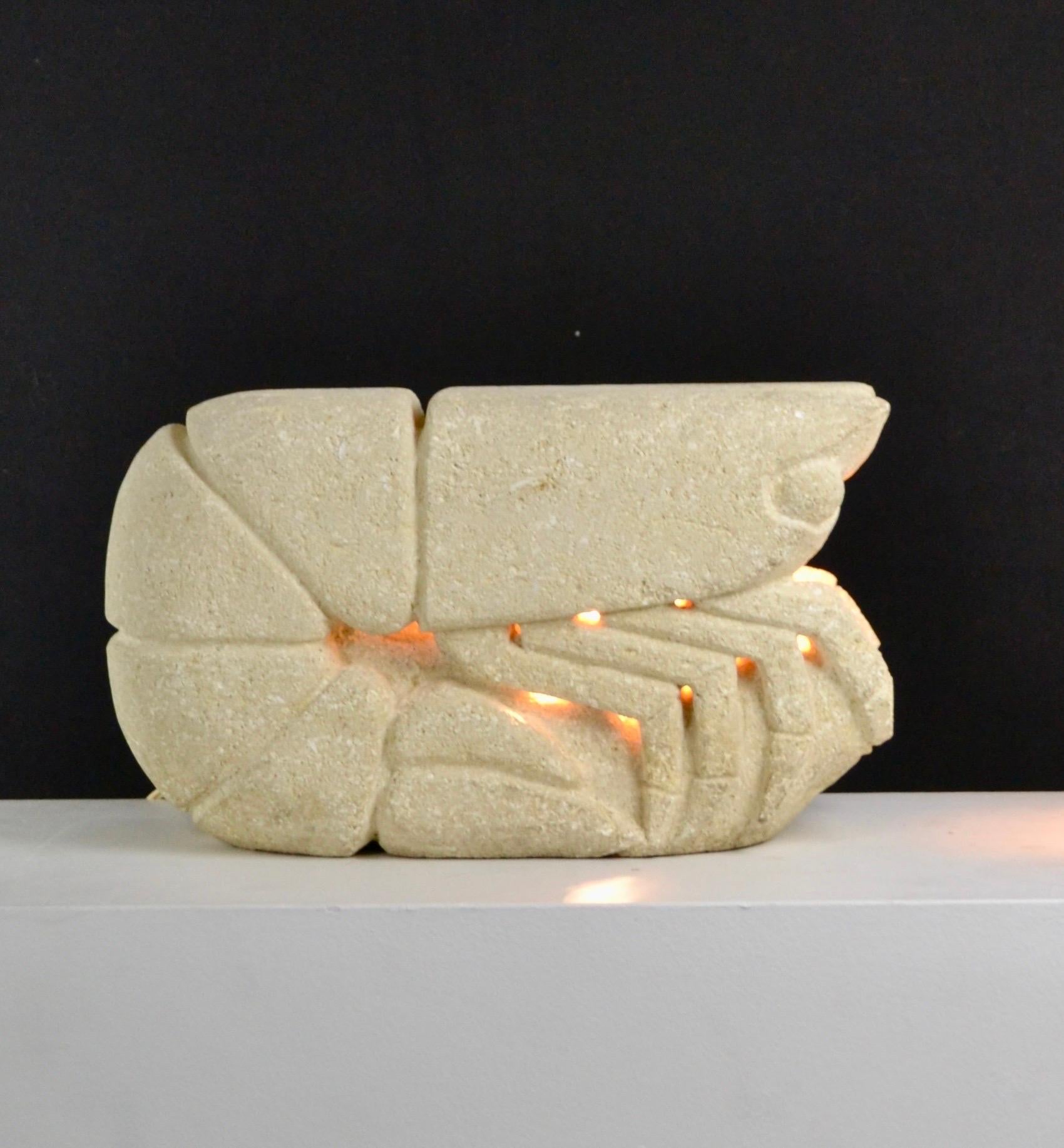 Cette lampe de table en pierre calcaire, vraisemblablement créée par Albert Condit dans les années 1970, est une pièce rare en parfait état. Sculptée en forme de crevette, elle reflète l'esthétique organique caractéristique de l'artiste, avec des