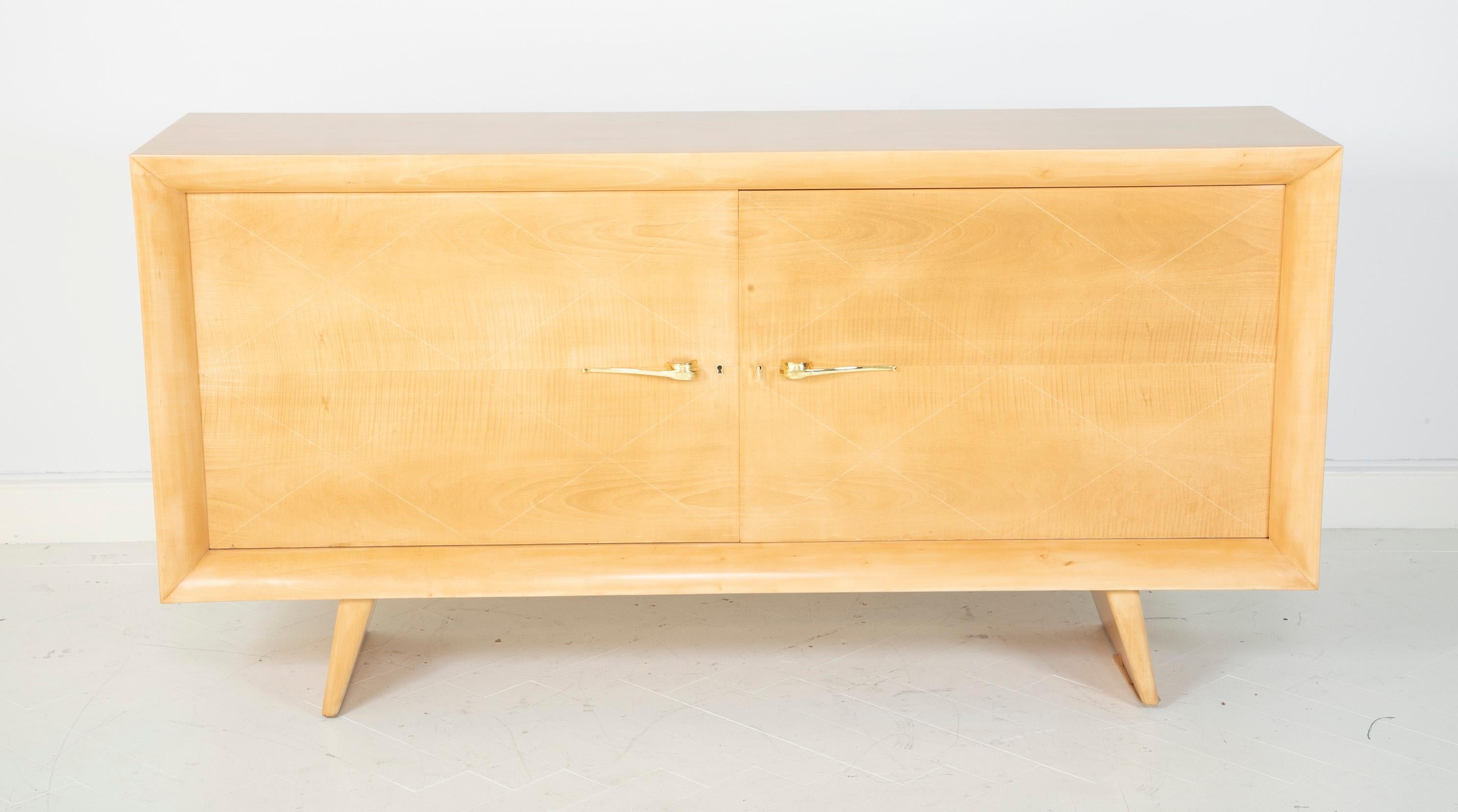 A maple credenza designed by Raymond Subes with light wood stringing inlay detail to doors.
Brass hardware.