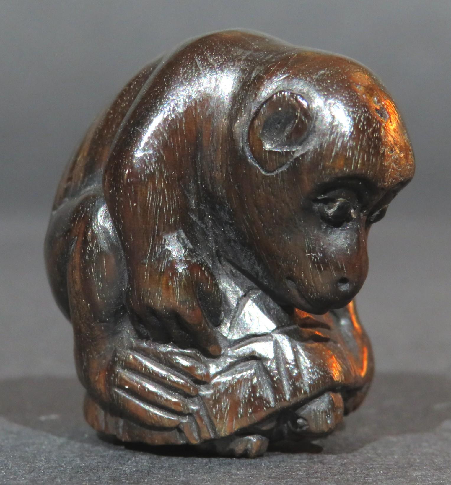 Un amusant netsuke en bois dur sculpté à la main de la période Showa (1926-1989) représentant un singe chevauchant une tortue, les yeux du singe étant incrustés de pupilles en cabochon, signé avec des caractères gravés sur le flanc gauche du singe. 