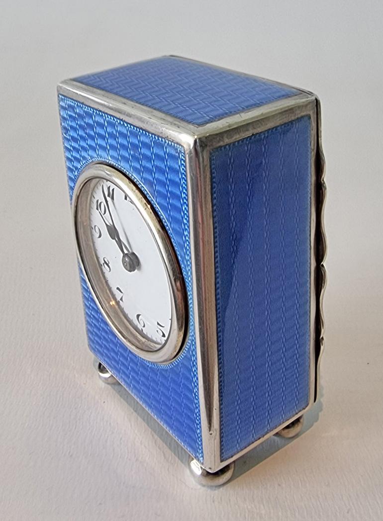 A very pretty silver and blue guilloche enamel miniature carriage or boudoir clock. Superb engine turned blue enamel. Sitting upon four bun feet. White enamel dial with arabic numerals, and blued steel hands. Fine full plate movement with platform