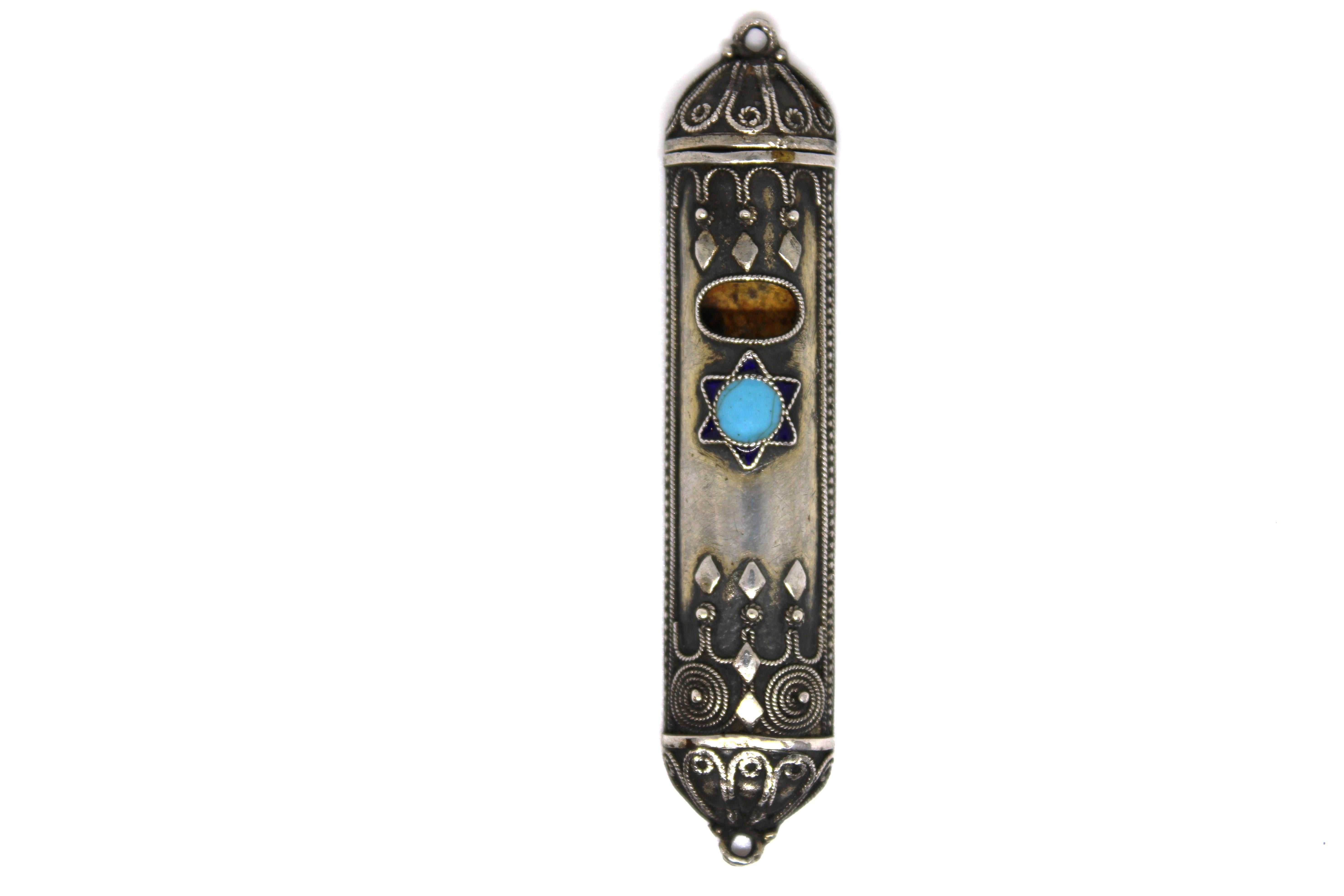 Dieses exquisite Mezuzah-Gehäuse, das Anfang bis Mitte des 20. Jahrhunderts in Israel hergestellt wurde, zeigt die meisterhafte Kunstfertigkeit der traditionellen Judaica. Das Gehäuse ist an den Rändern und Seiten mit filigranen Schnörkeln verziert,