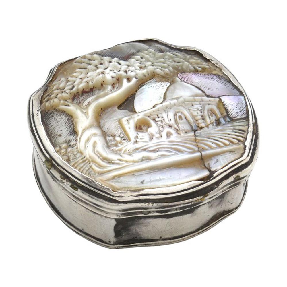 Esta extraordinaria caja de rapé es una auténtica obra de arte, elaborada en plata y adornada con una impresionante tapa de nácar. A diferencia de los diseños tradicionales rectangulares o en forma de caja, esta pieza adopta la forma única y