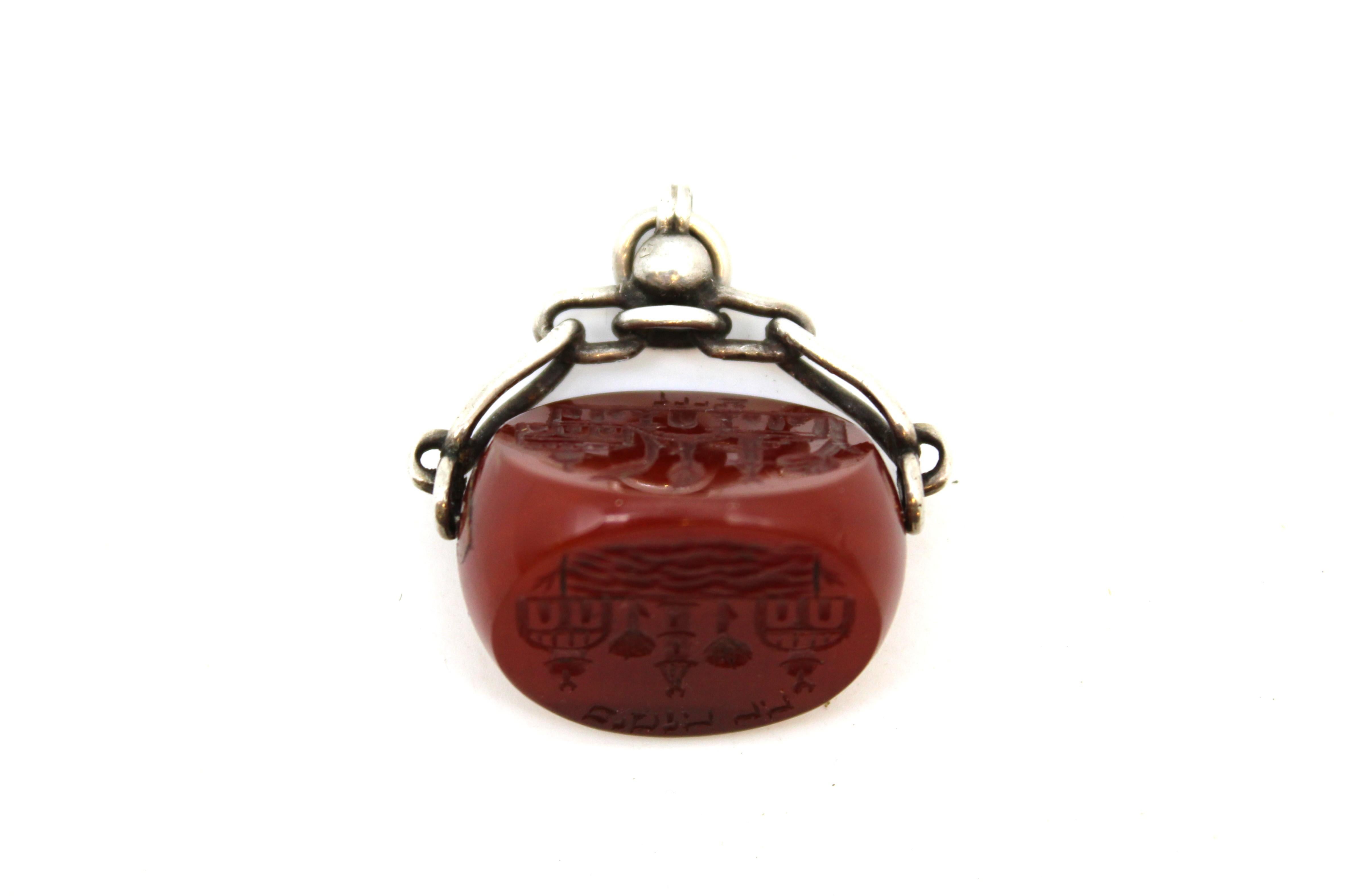 This exquisite and highly unusual Judaica object is a rotating Jerusalem seal, crafted circa the early 1900s, combining fine silverwork with a richly hued ruby-colored stone. Ingeniously designed, the central seal stone is mounted on a rotating