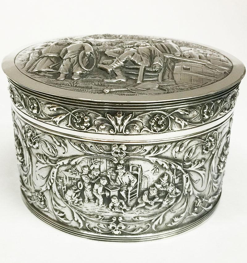 A silver box with lid from the 20th century

The silver box is the scene  in relief after the oil painting of Jan Steen (1626-1679)
