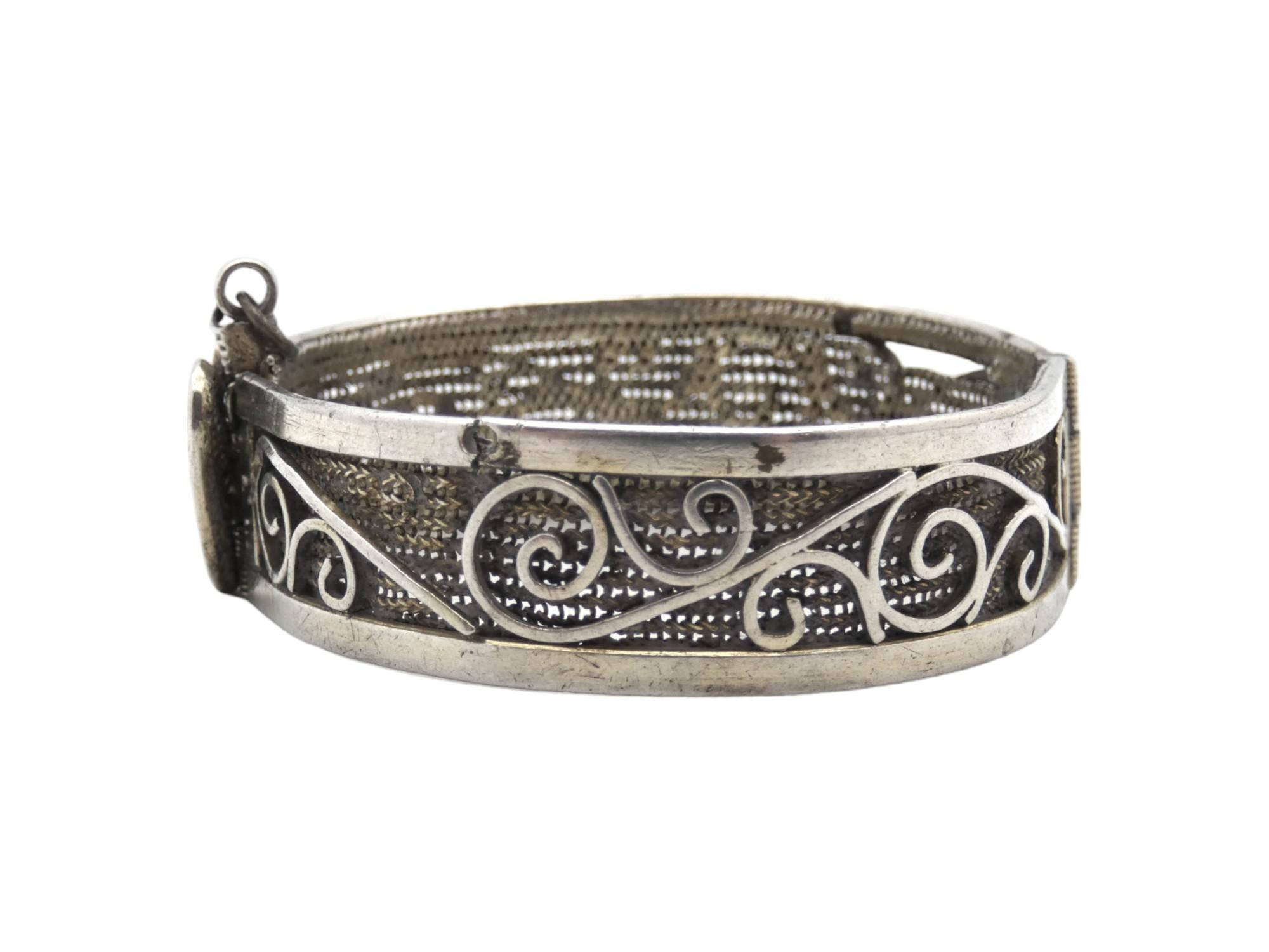This charming Yemeni silver bracelet, crafted circa 1900, was designed with the youthful elegance of a young woman in mind. The bracelet features an intricate openwork composition of ornamental scrolls and decorative patterns, gracefully framed