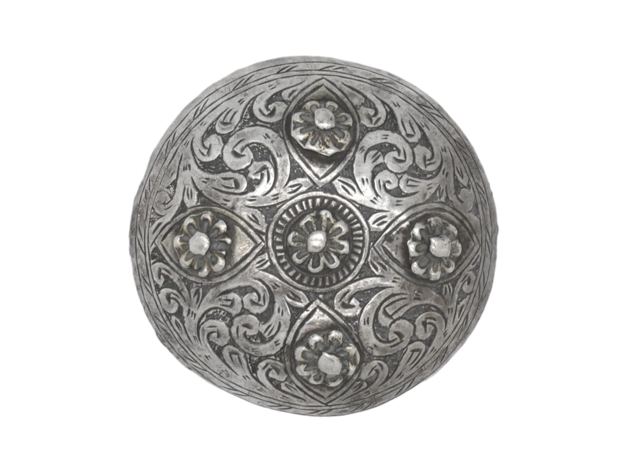 This elegant silver brooch, crafted in Morocco circa 1900, is a beautiful testament to the refined artistry of North African jewelry traditions. The surface of the brooch is richly adorned with multiple raised rosettes, each meticulously crafted to