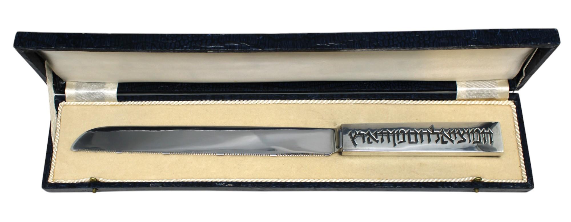 Este exquisito cuchillo para Challah con mango de plata, diseñado por el renombrado artista de Judaica Ludwig Yehuda Wolpert, es una asombrosa mezcla de artesanía modernista y profundo simbolismo religioso. El asa está tallada con la bendición