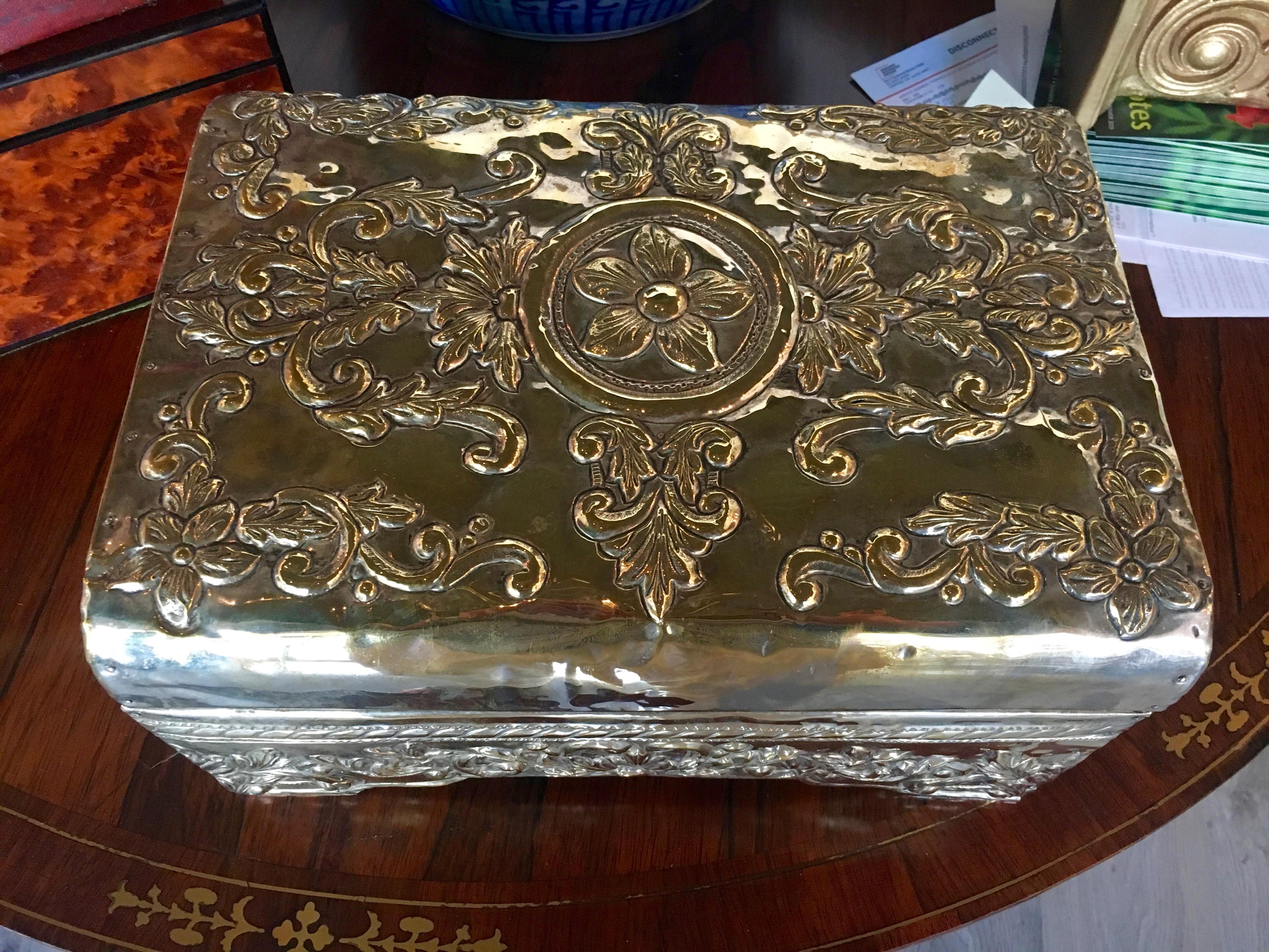 A silver-clad table casket

the domed hinge top centered with a paterae among foliate scrolls. 
apparently unmarked This has a golden patina.
Height 7 1/2 x width 14 x depth 10 inches.
