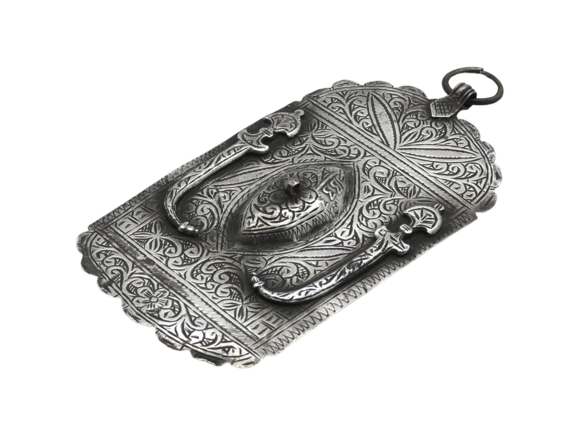 L'A. Silver Hamsa, proveniente dal Marocco dell'inizio del XX secolo, è un manufatto affascinante che fonde il simbolismo ebraico con l'artigianato nordafricano. 

L'Hamsa, un amuleto a forma di mano che si ritiene possa allontanare il malocchio e