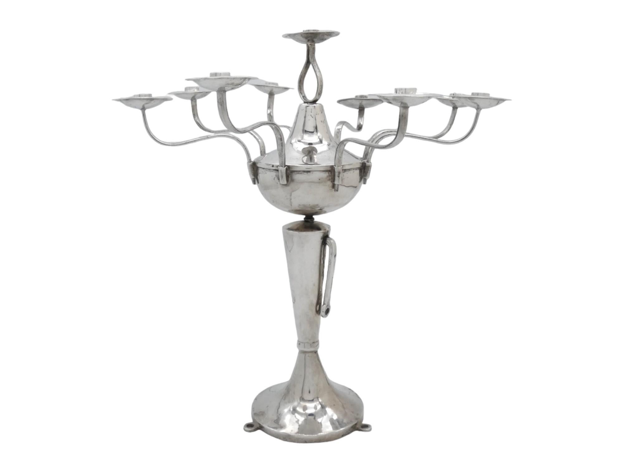 Questo modello regolabile in argento  Il candelabro Hanukkah dell'Iraq del 1900 circa è un pezzo unico e storicamente significativo di Judaica. Questo tipo di menorah riflette sia le pratiche religiose che le tradizioni artistiche della comunità